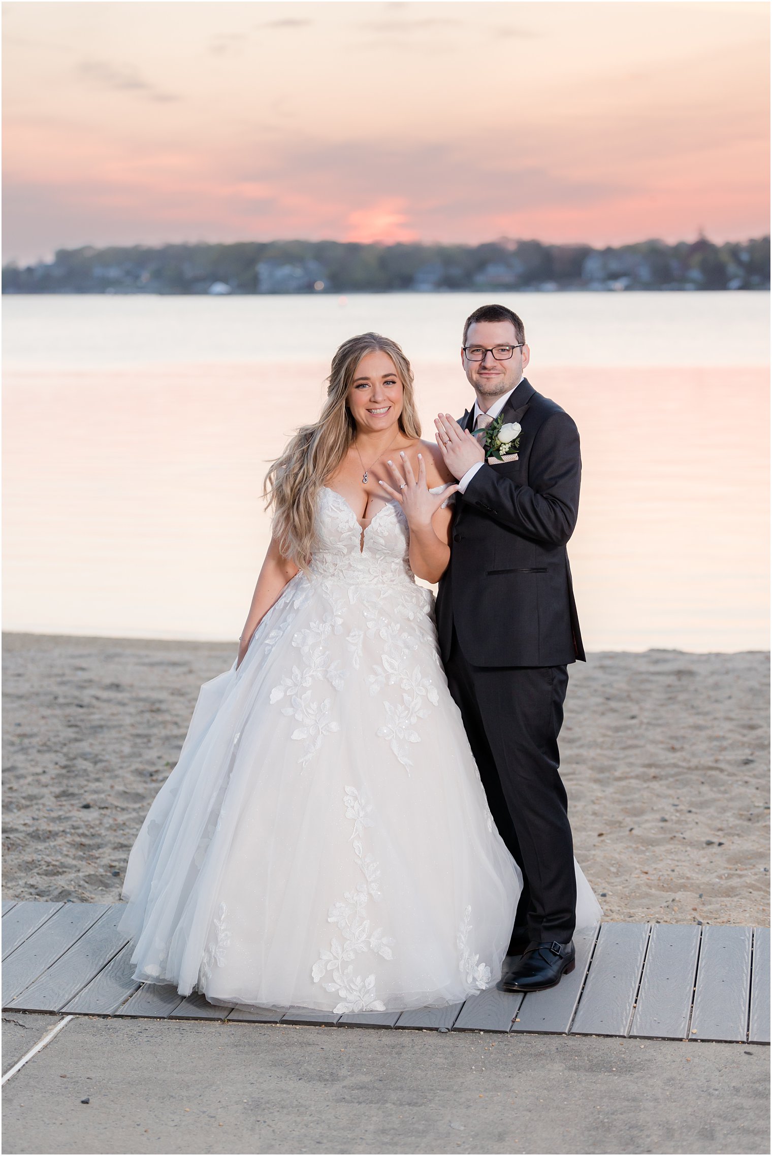 bride and groom show off rings stand on beach in Pleasant Point NJ at sunet