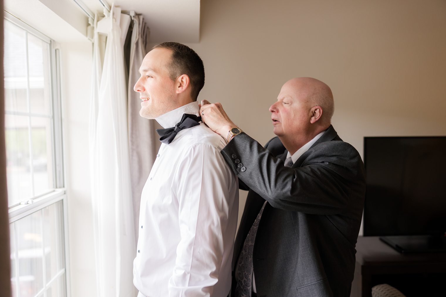 Father of the groom helping his son to get ready for wedding at Indian Trail Club