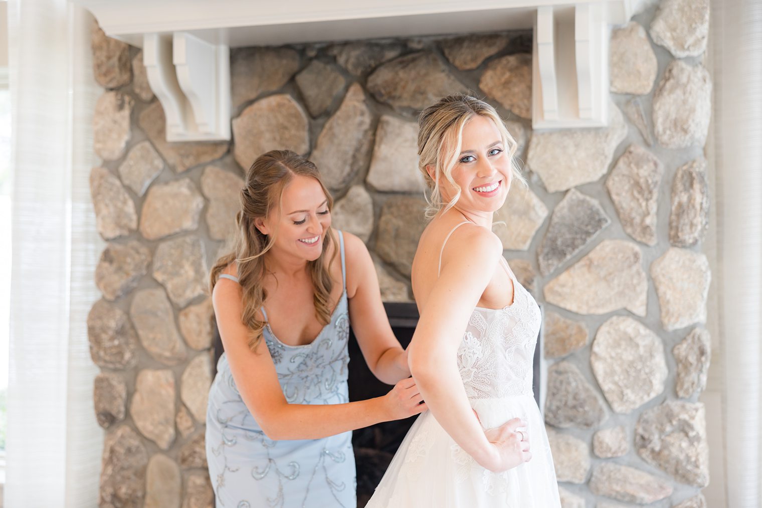 bridesmaid helping the bride with her dress at Indian Trail Club