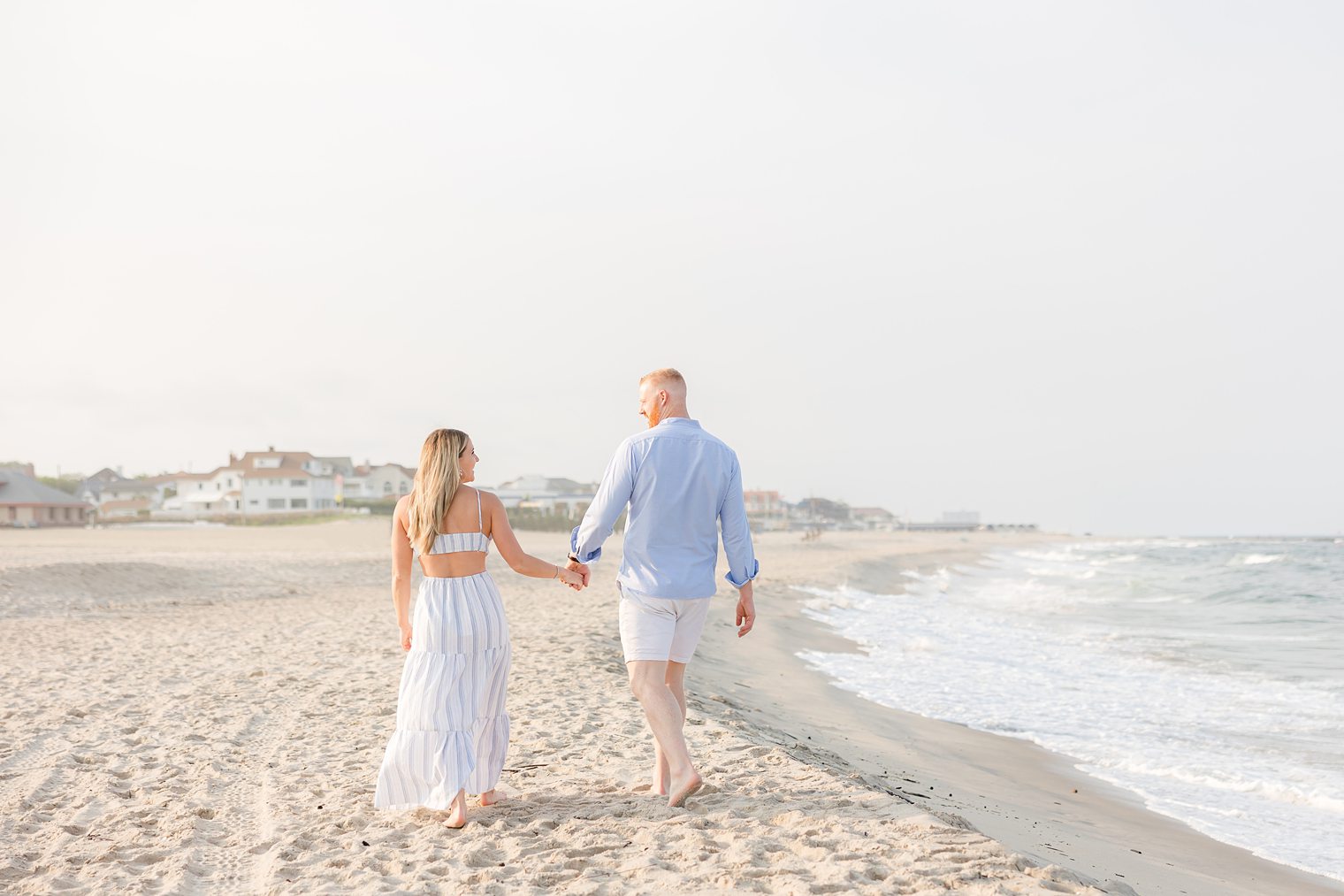 Bride and Fiancé holding hands while the walk in the sand 