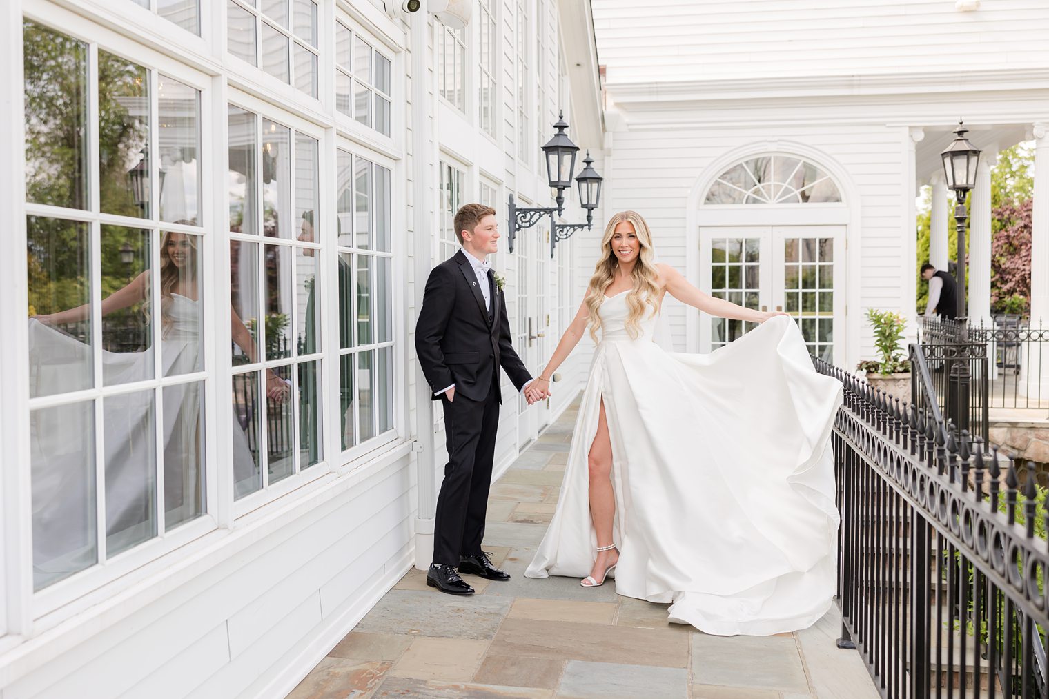 Bride and Groom holding hands while the bride shows up her dress 