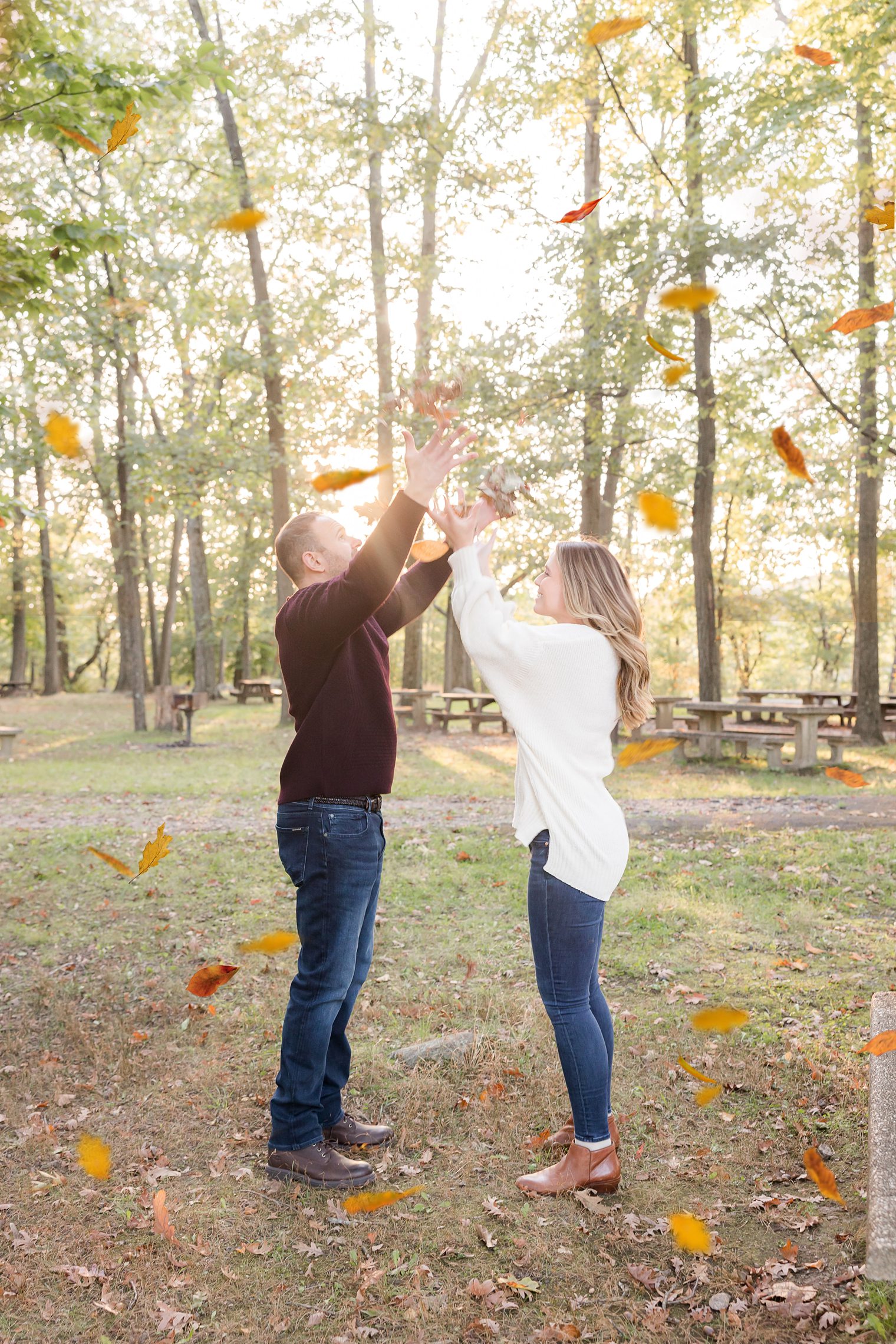 couple playing with tree leaves at their engagement session 