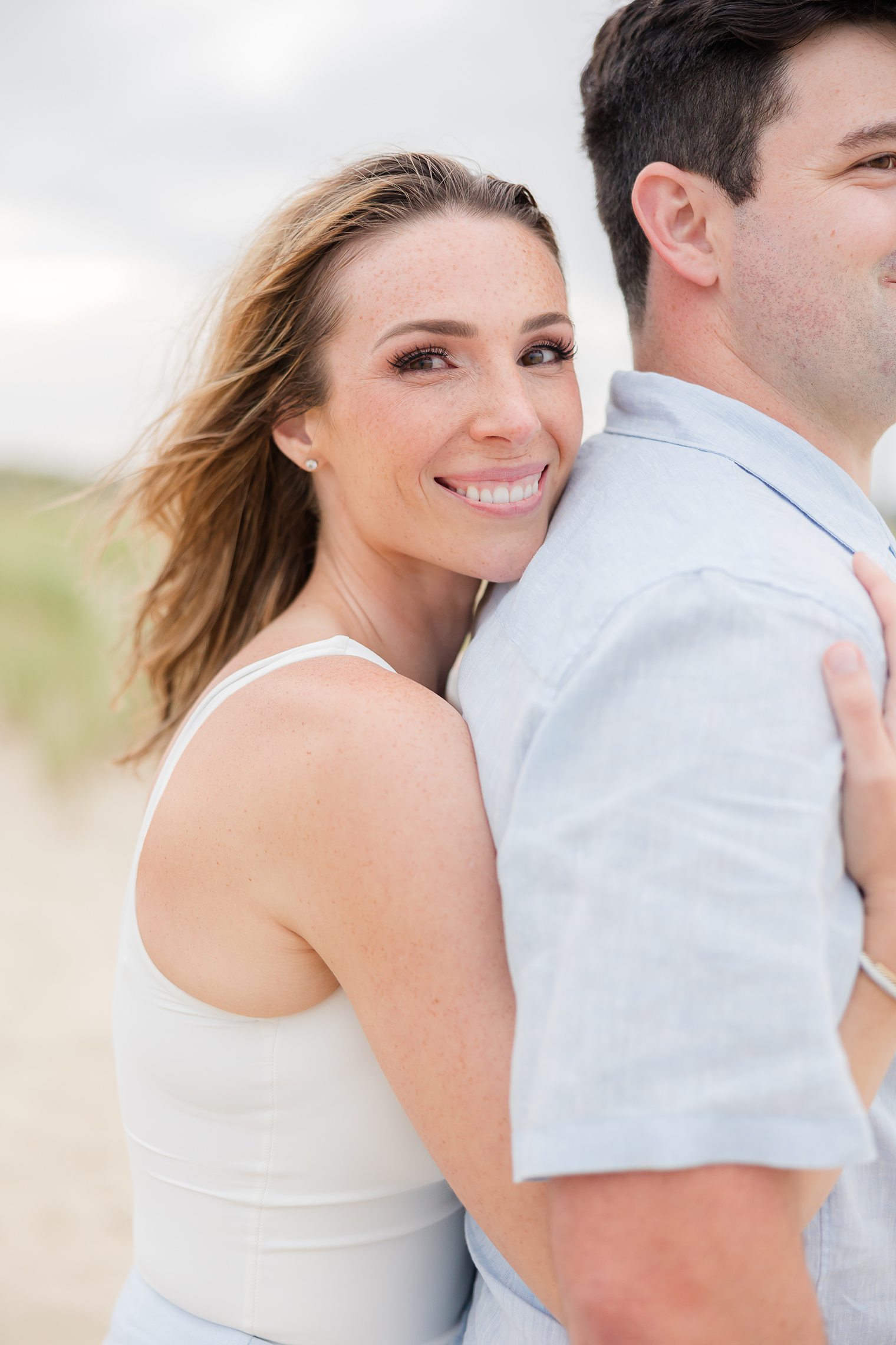 bride hugging her fiancé from behind 