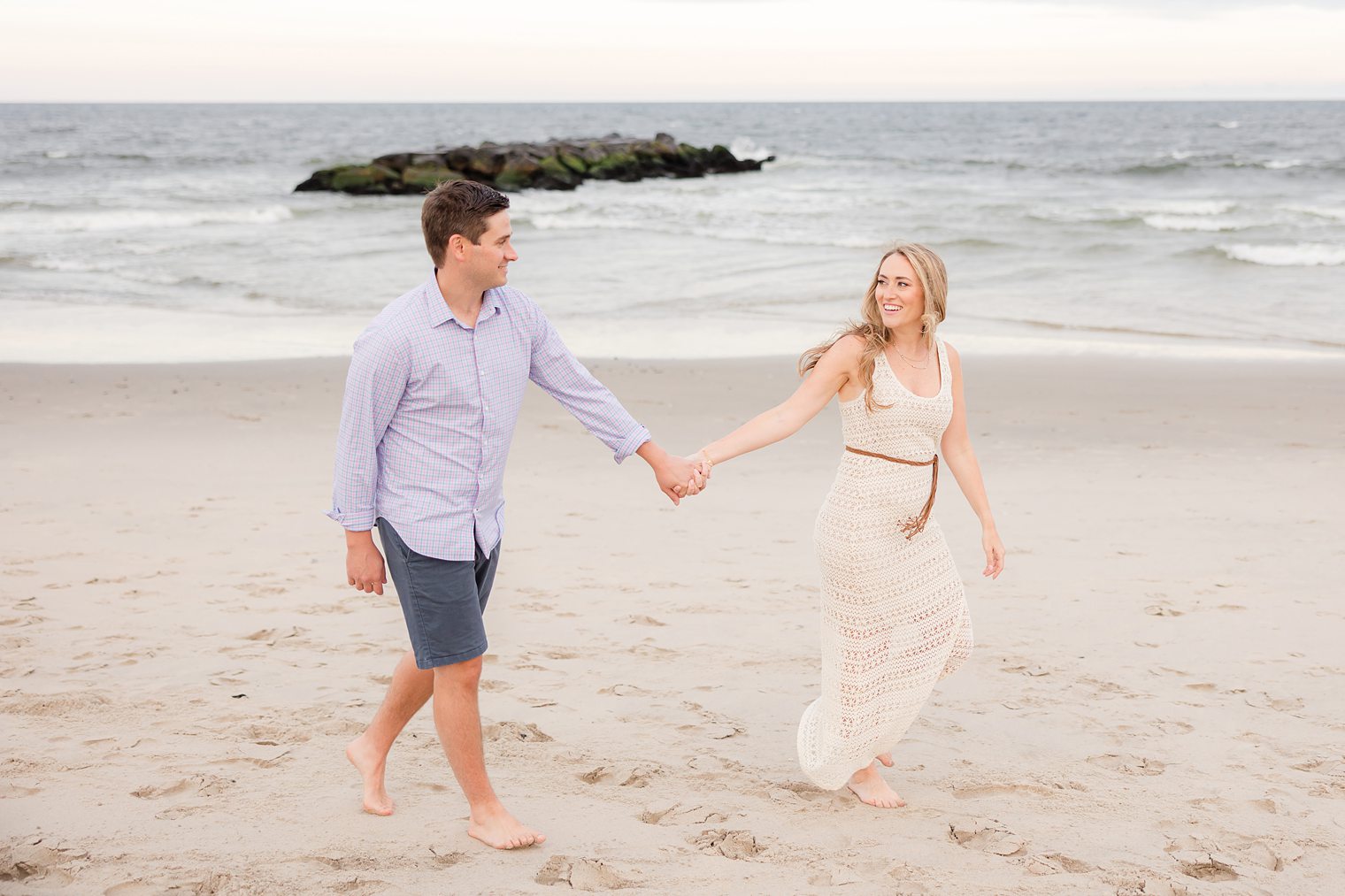 bride and future husband walking in the beach holding hands 