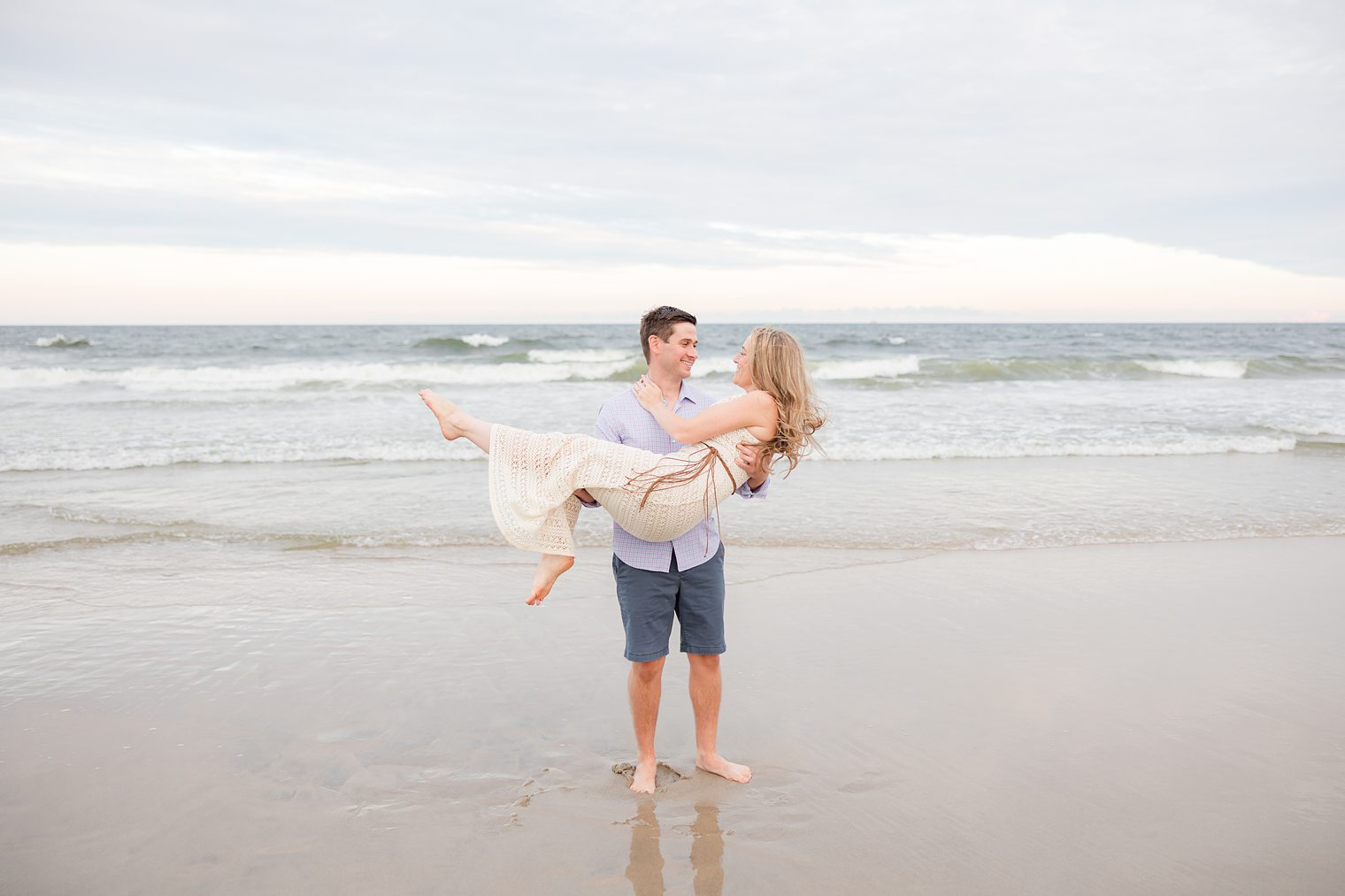 fiancé holding up his bride at the beach
