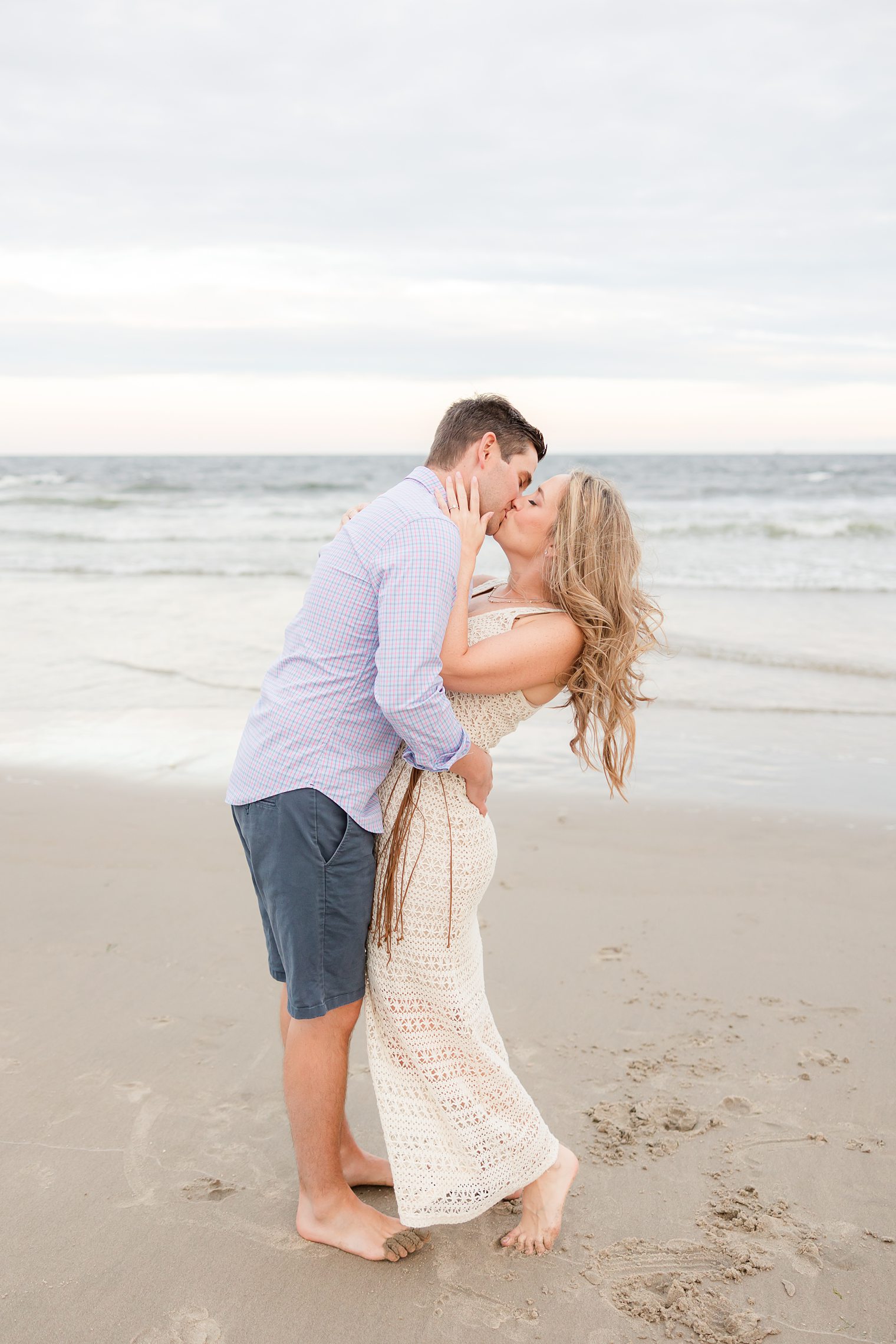 Future husband and wife kissing with the beach as backdrop