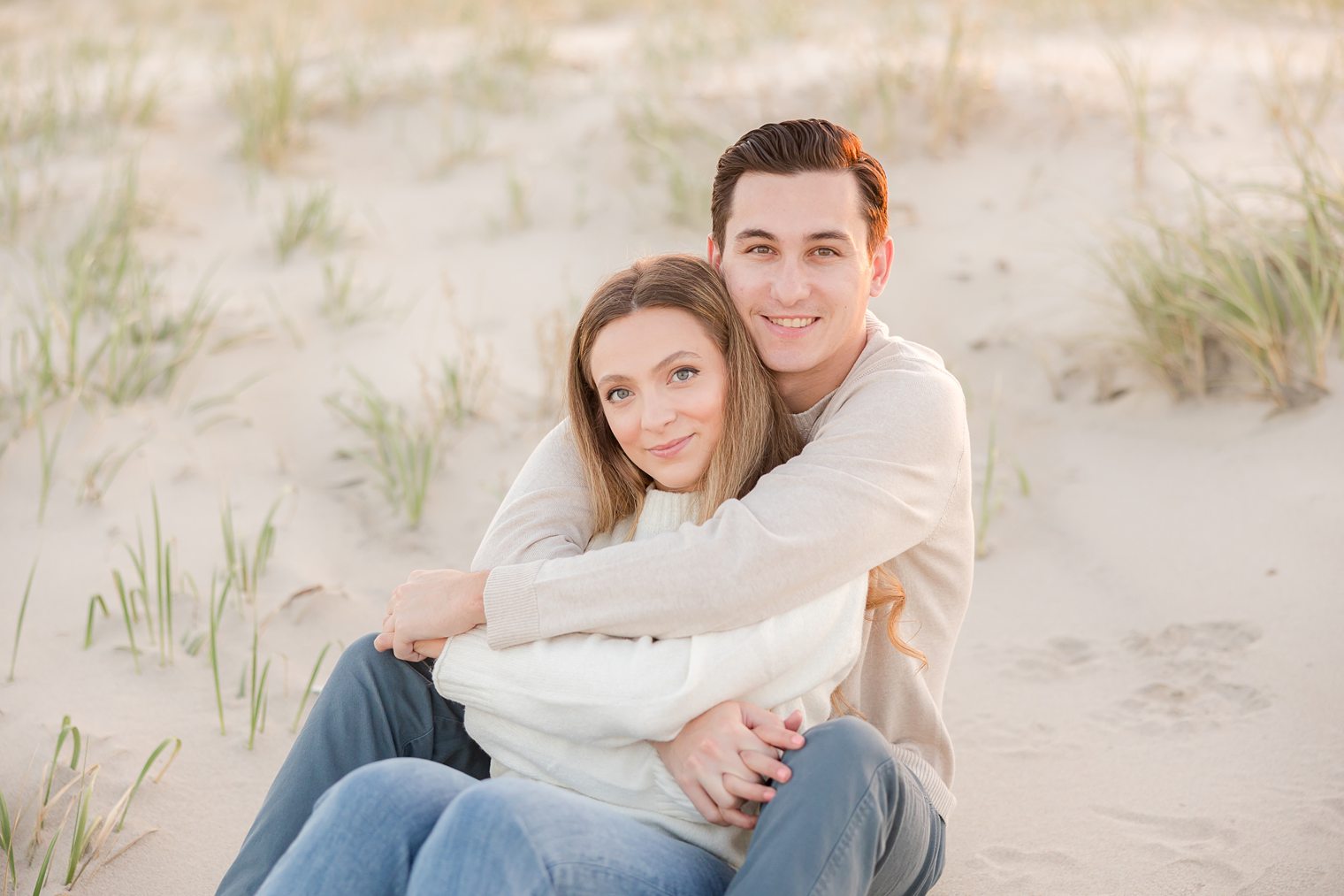 fiancé and bride sitting on the sand at spring lake