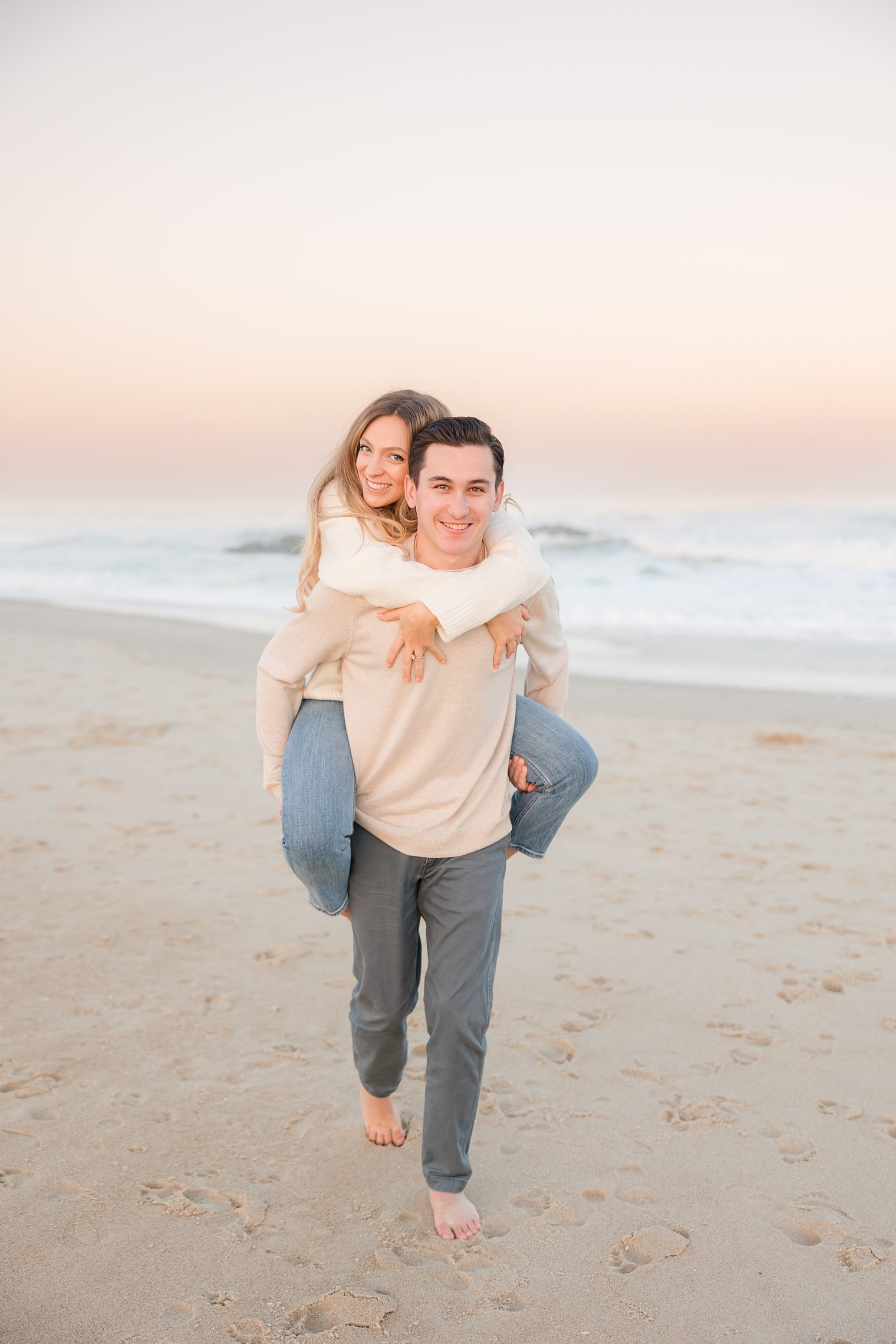 Fiancé holding up his bride in his back to take her for a walk in the beach