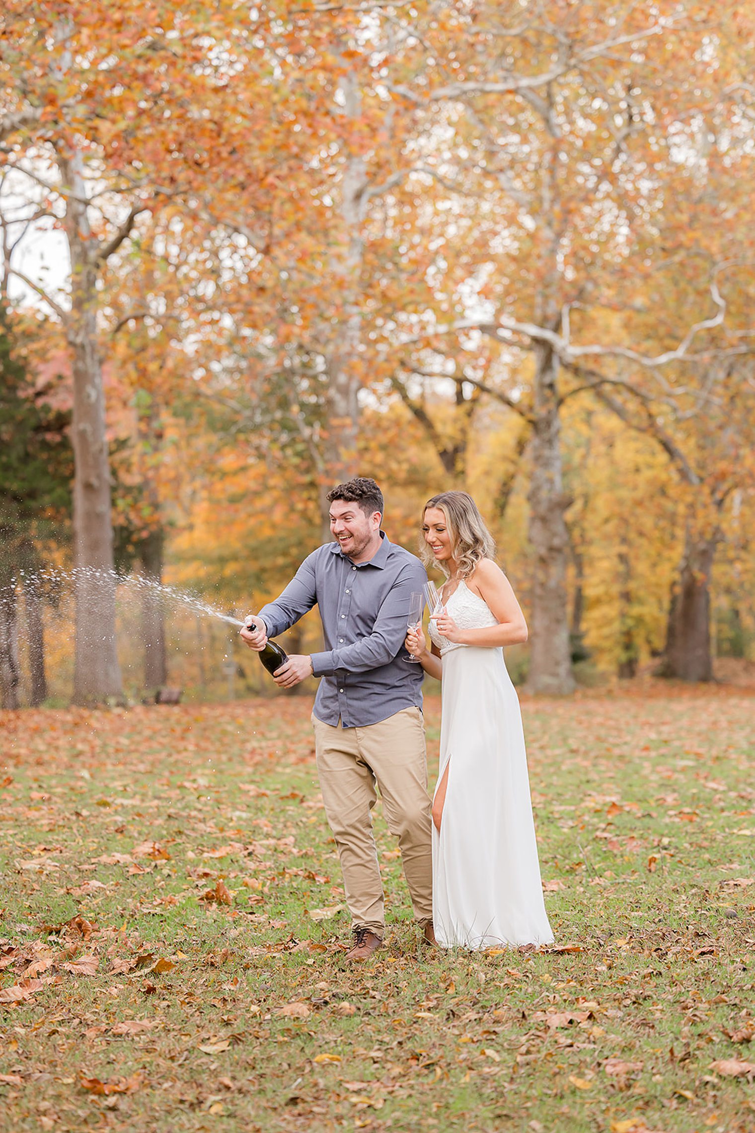 Future husband and wife popping a bottle of champagne in their engagement session
