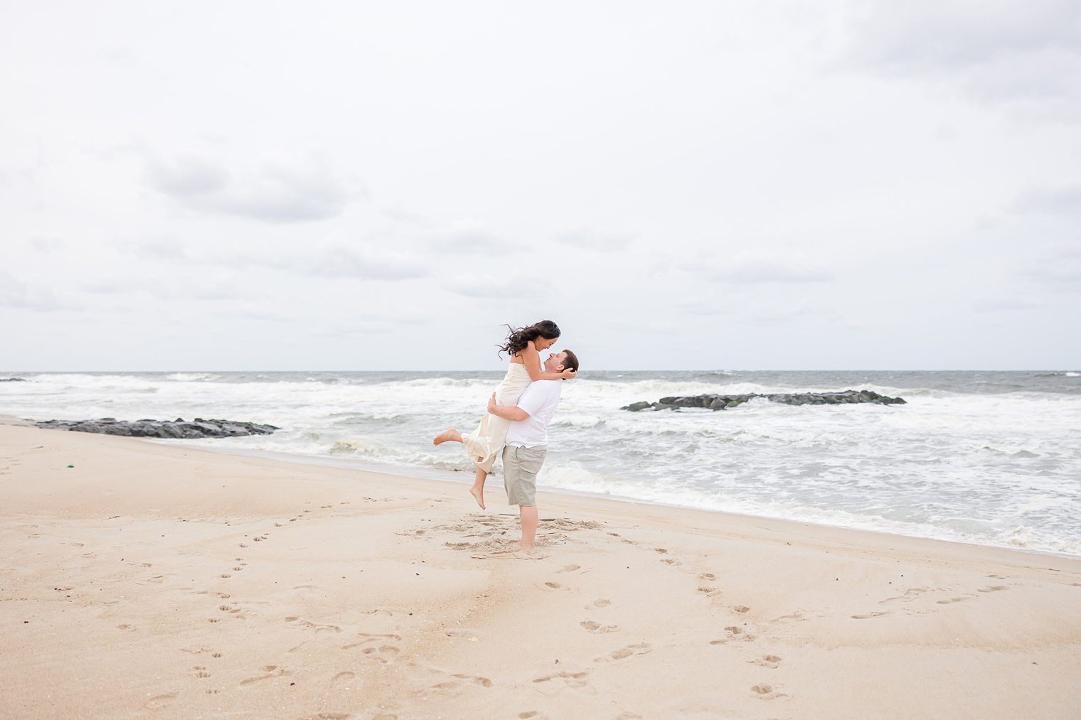 fiancé holding up to his bride at the beach 