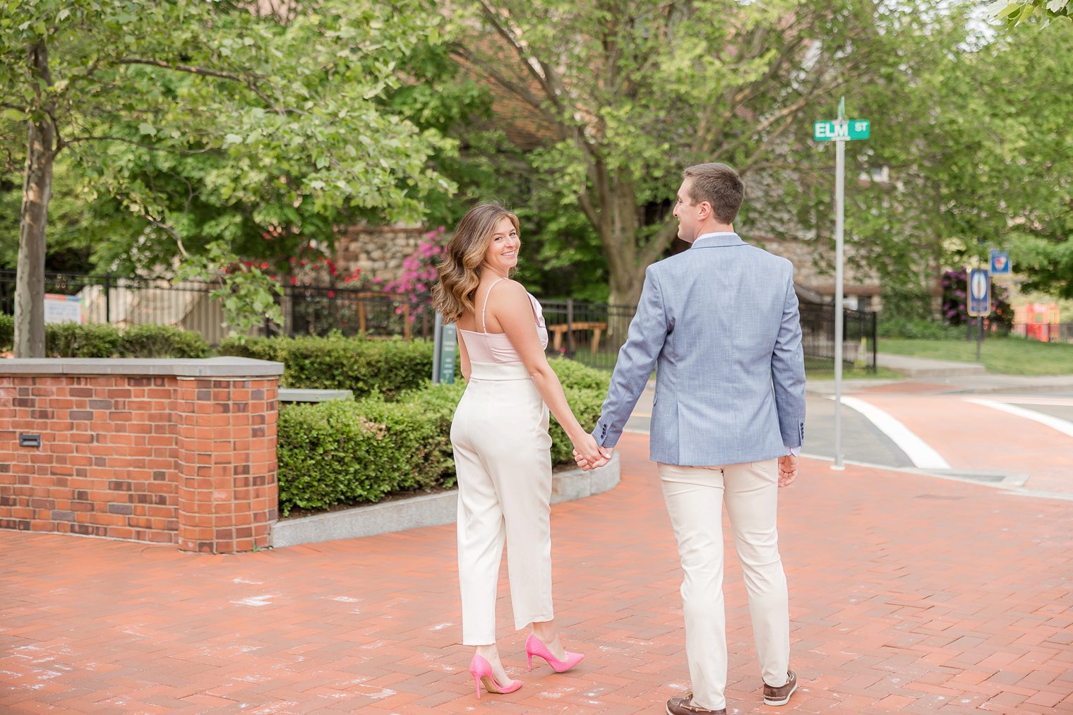 future husband and wife walking holding hands, bride looking to the camara 