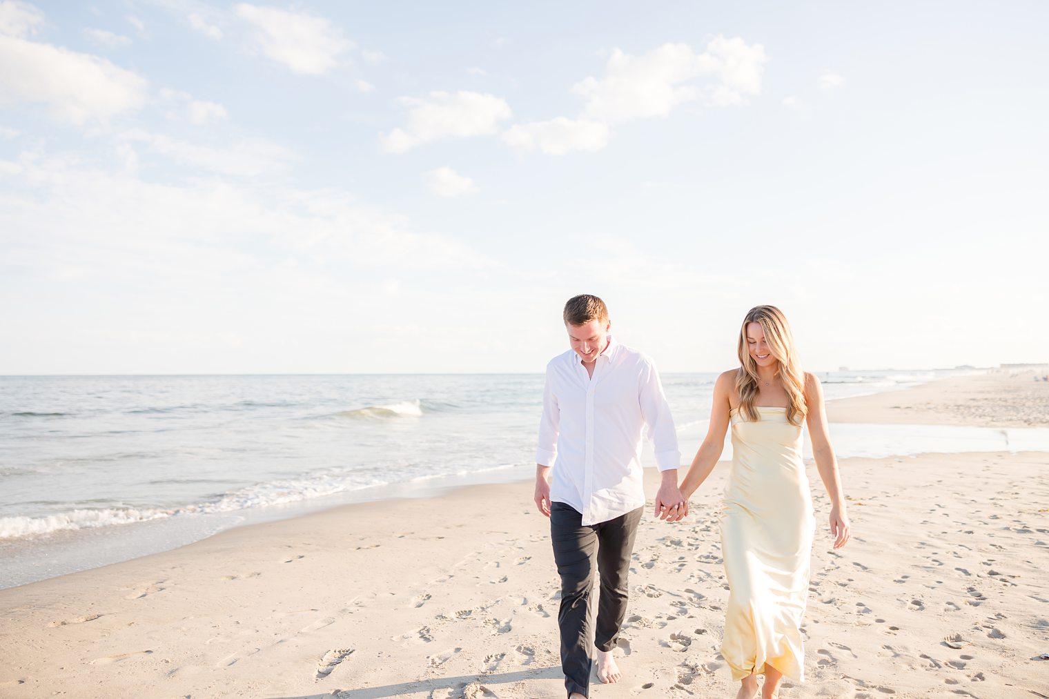 future husband and wife taking a walk in the beach while they hold their hands