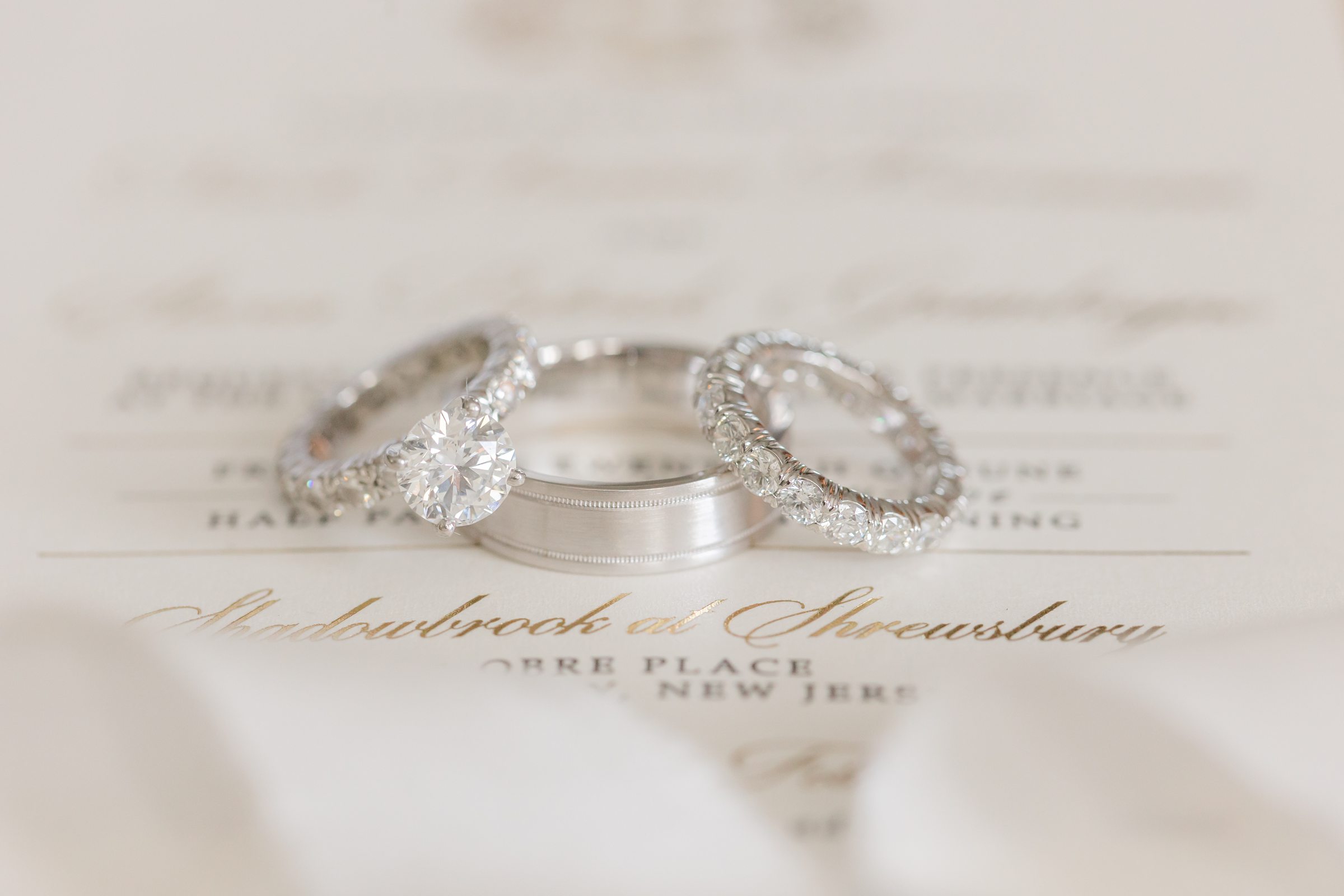 beautiful wedding bands and engagement rings on invitation to wedding at Shadowbrook in Shrewsbury, NJ