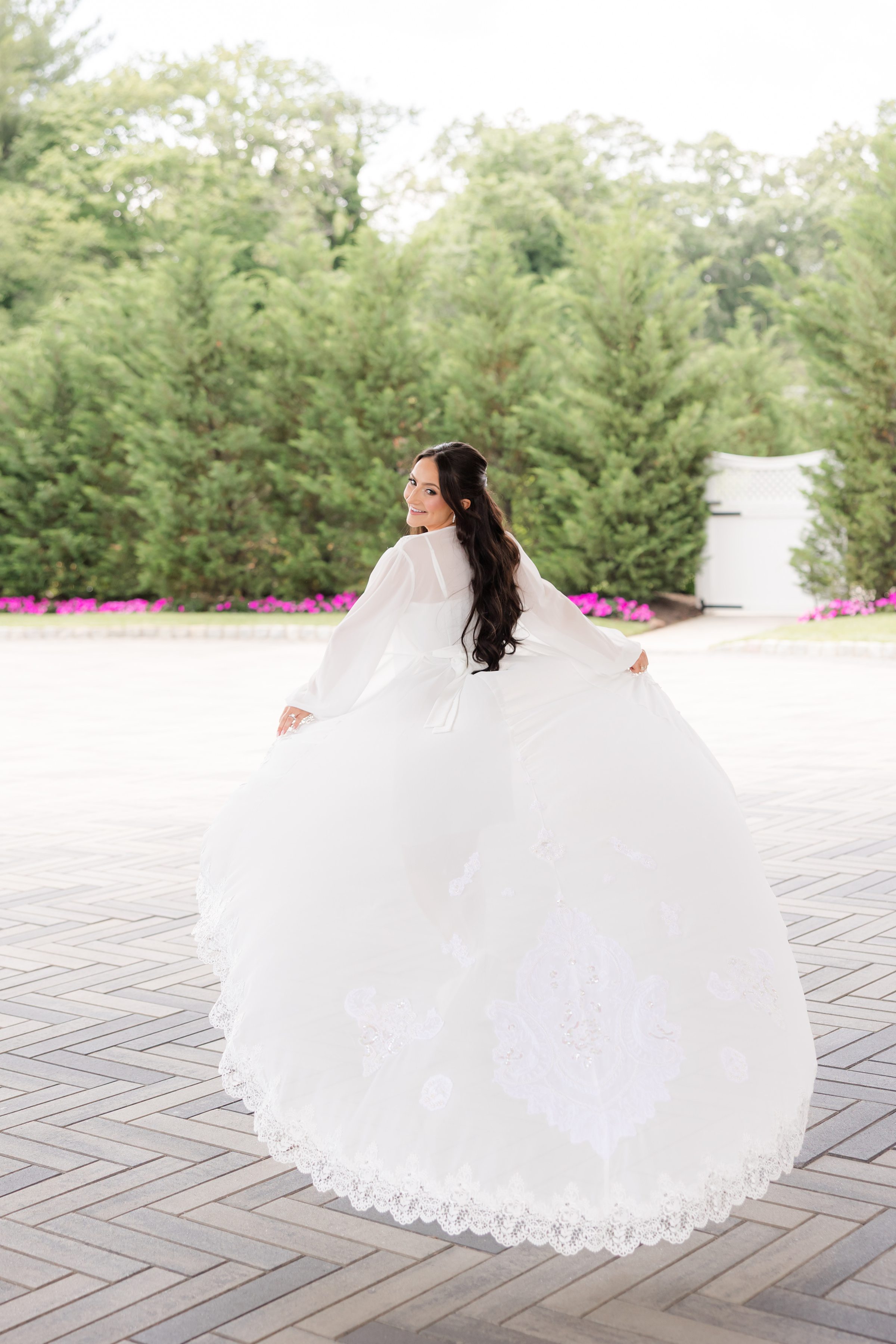 Bride is smiling, showing the back details of her white lace robe