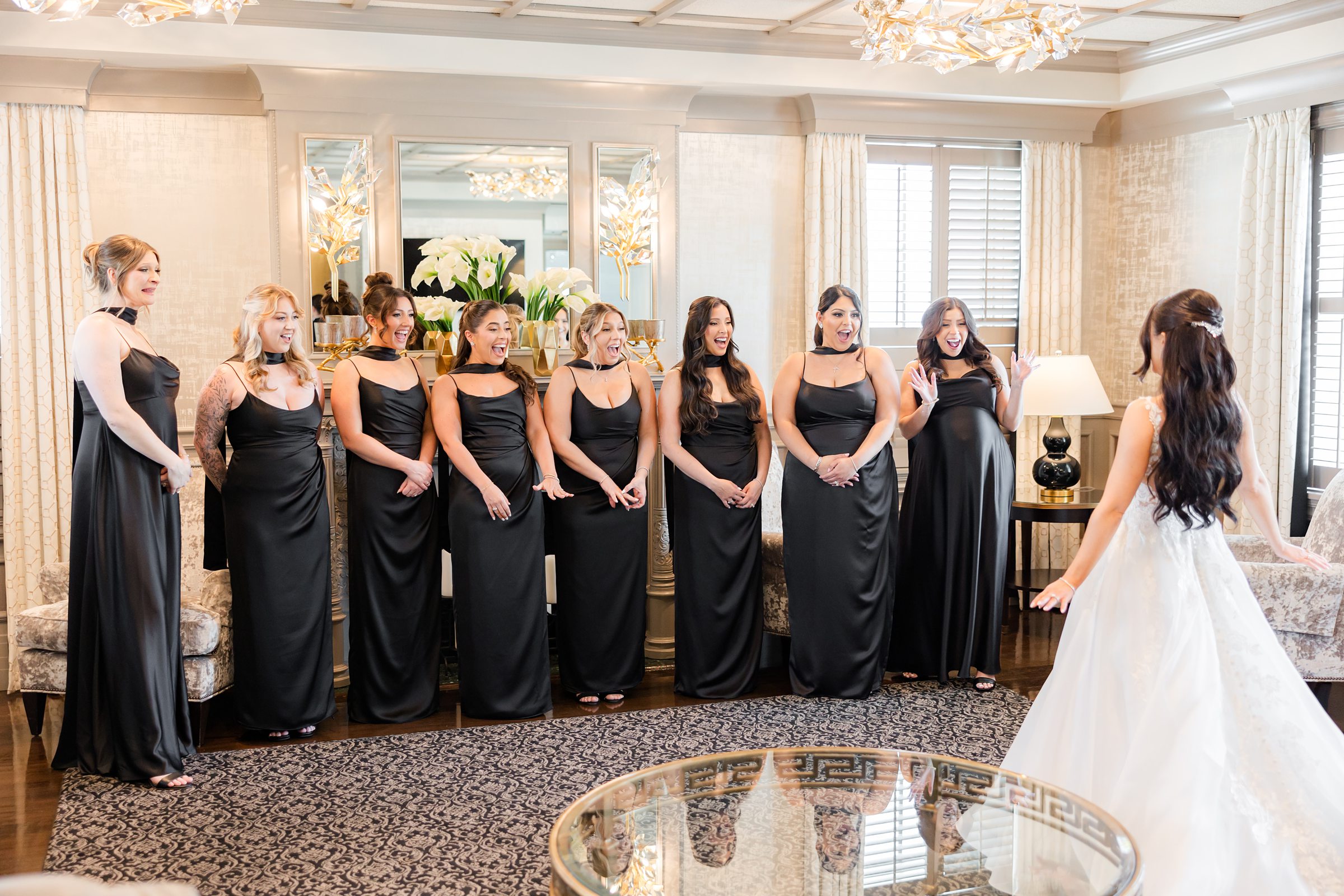 Bride is showing herself to the bridesmaids wearing the lace wedding dress, bridesmaids are wearing black dresses. 