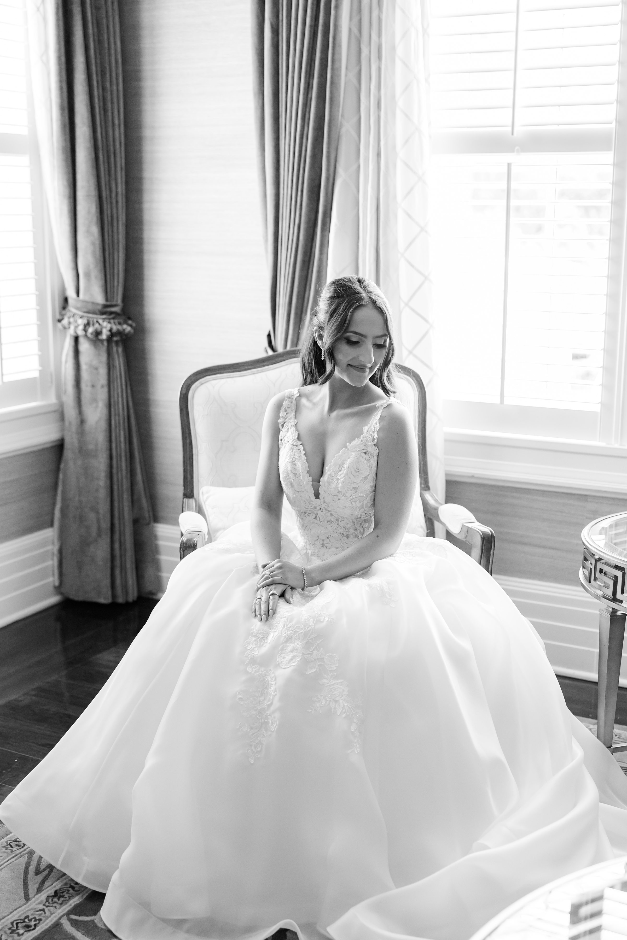 Bride is sitting, wearing a wedding gown while looking down the side.