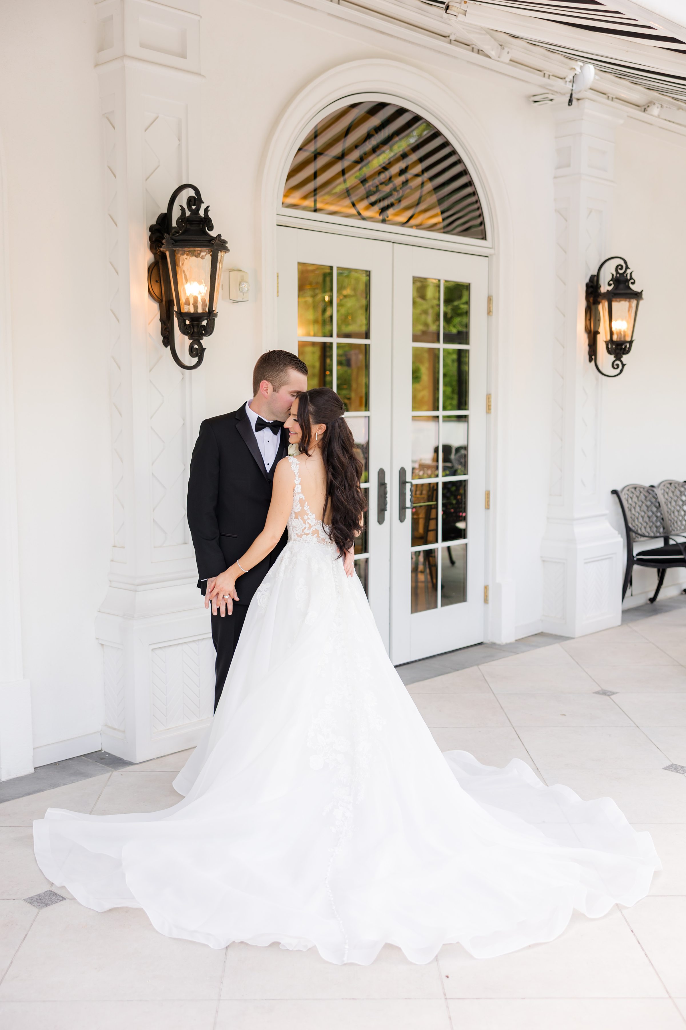 Picture of groom and bride posing together, holding each other's hands by the reception door.