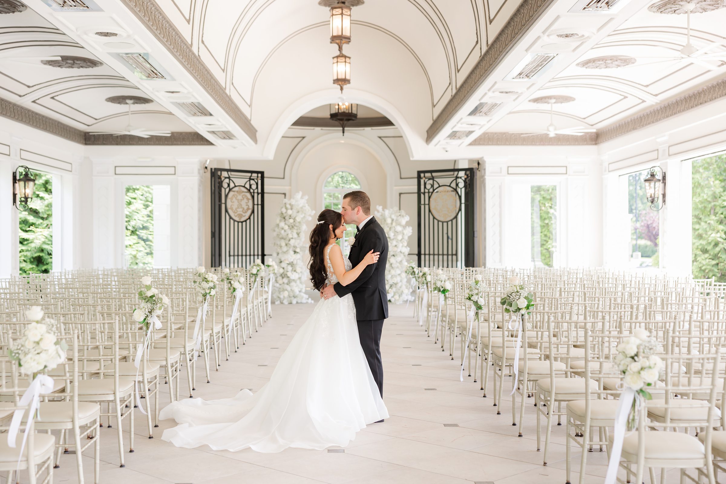 Groom is kissing the bride's forehead in the reception hall