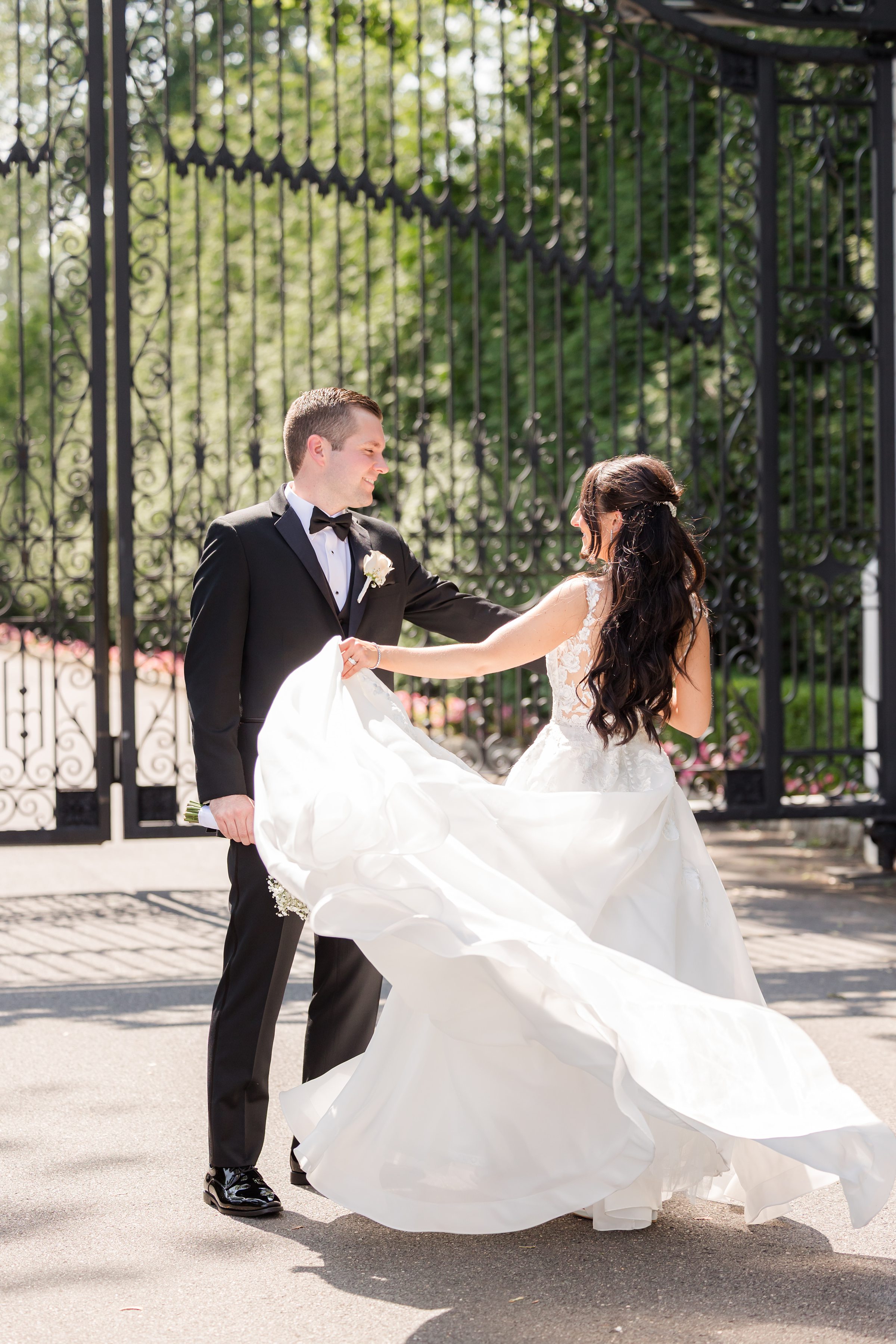 The couple are having their sweet moments by the gate, the bride is swaying her wedding dress