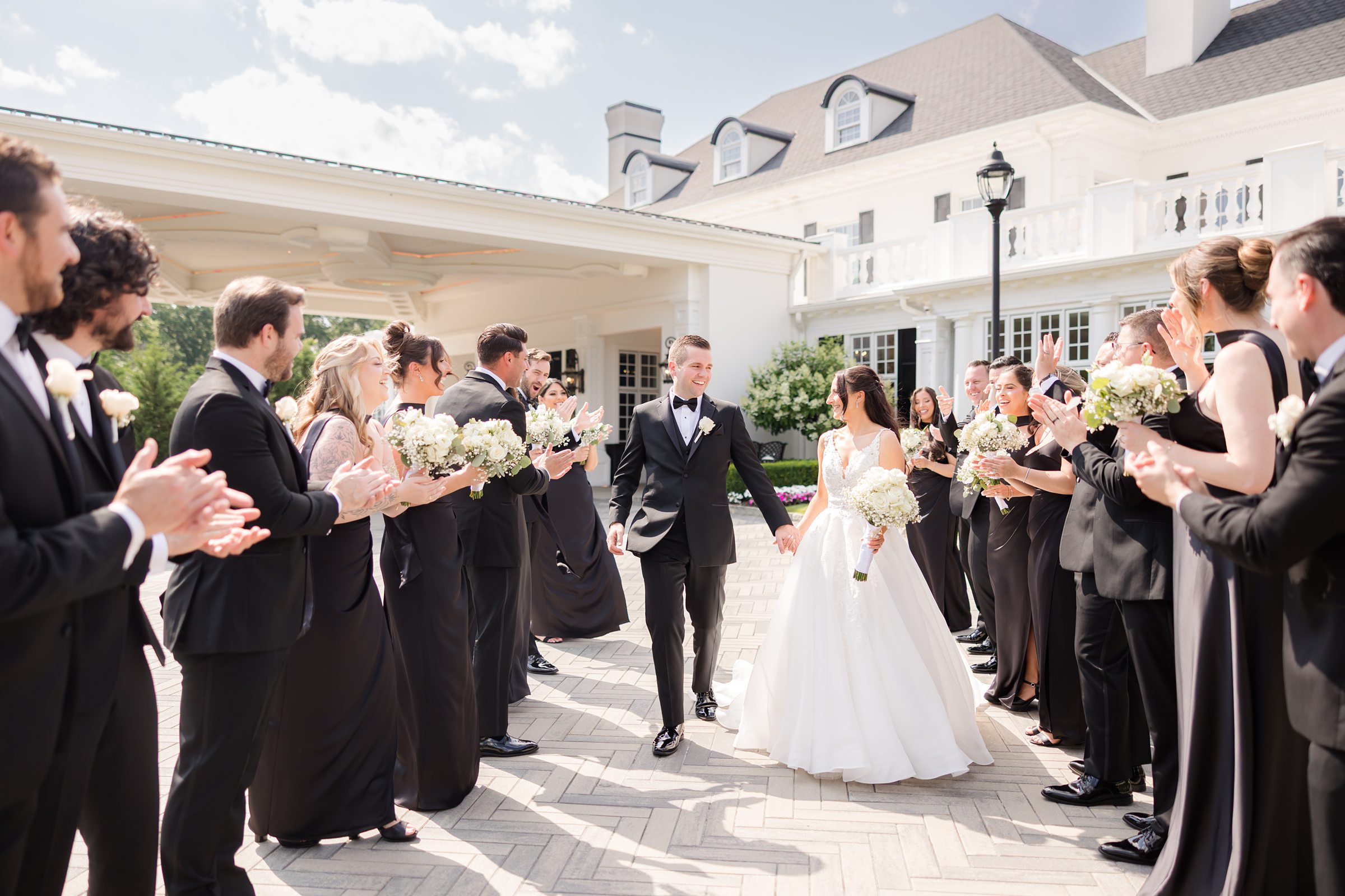 Bridesmaids and groomsmen are cheering for bride and groom as they walk together in the center