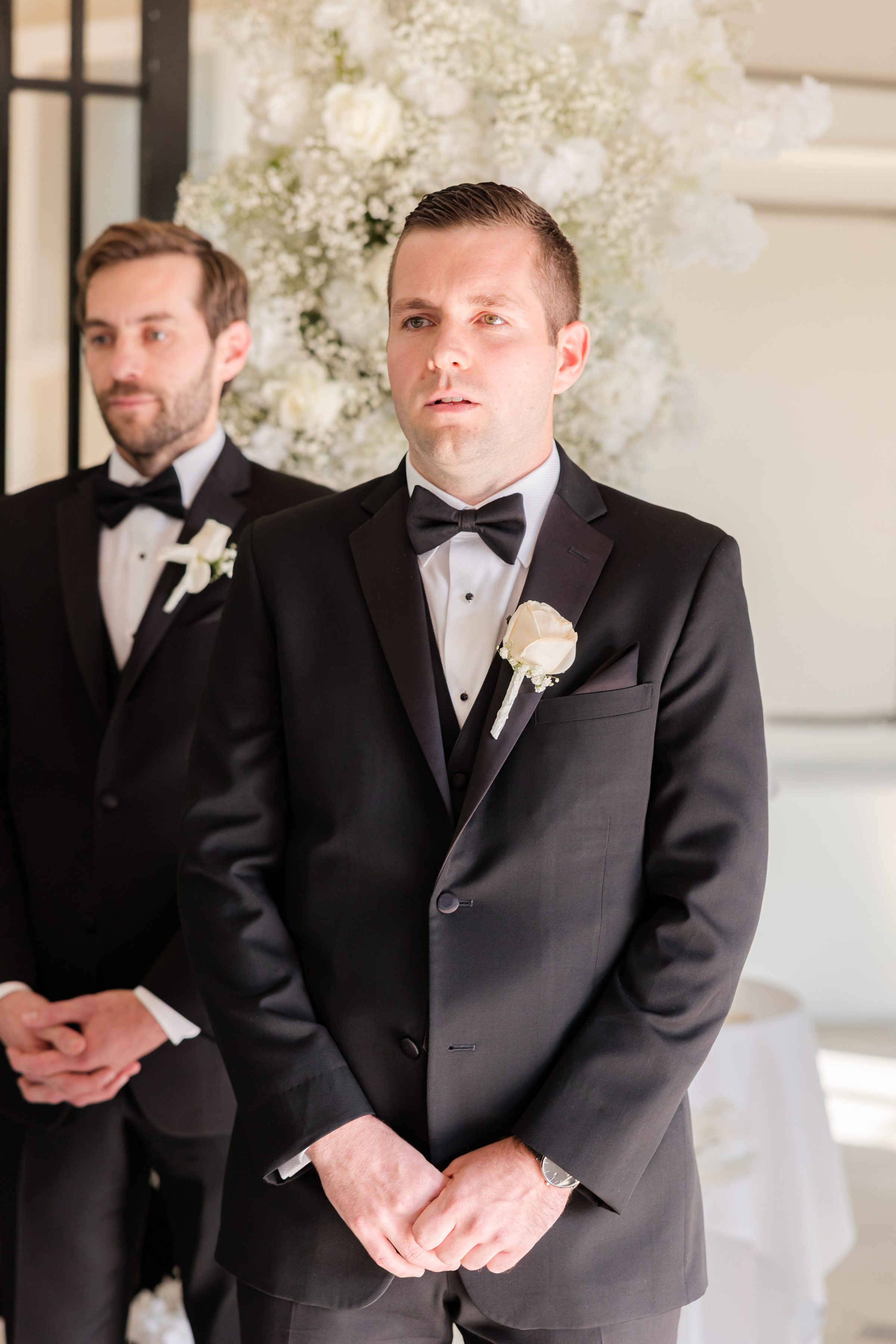 Groom is looking at the bride while her parents walk her down the aisle 