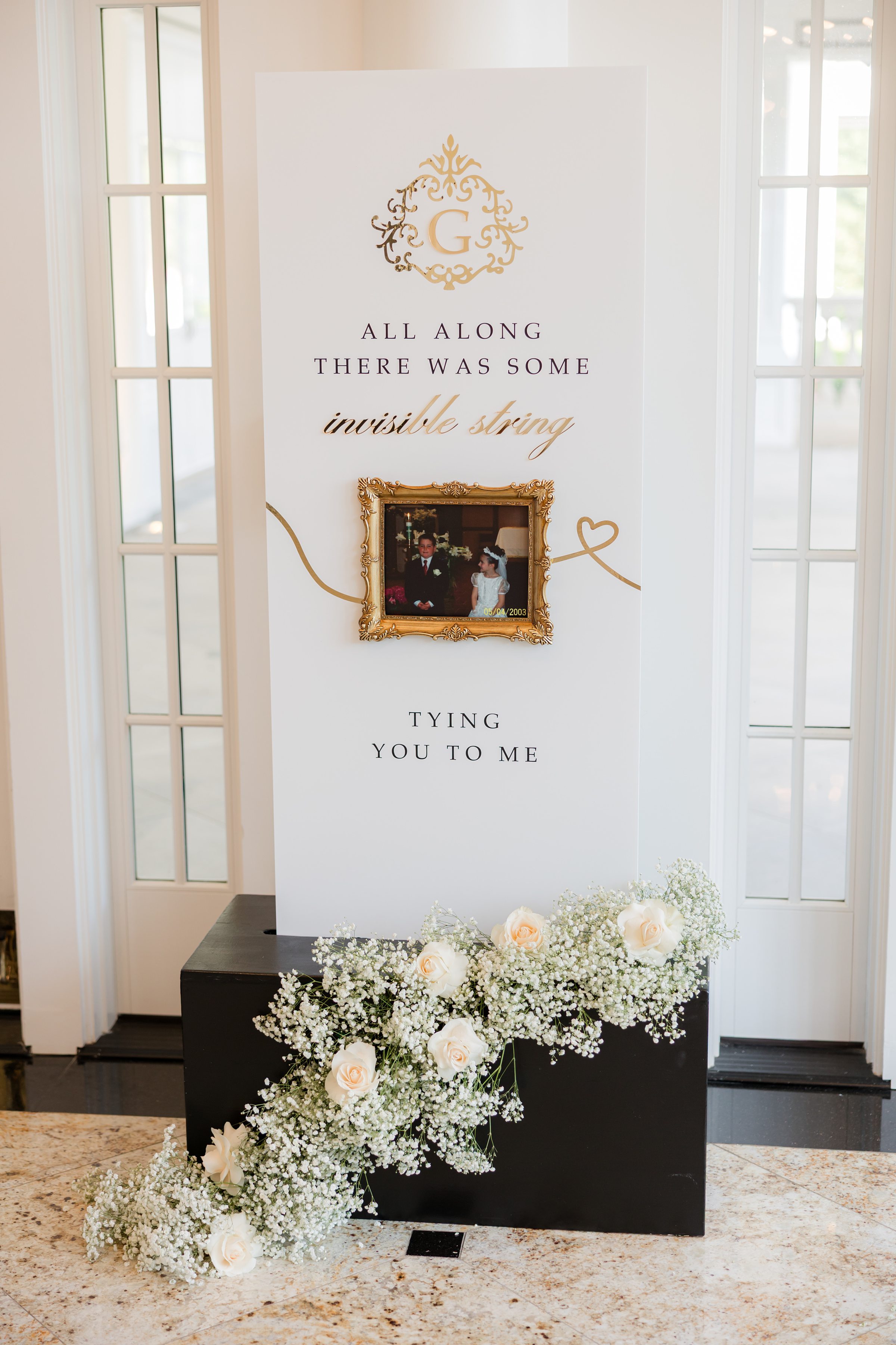 a wedding board with the couple's old picture back in 2003, young girl is wearing white dress and the young boy is wearing tuxedo 