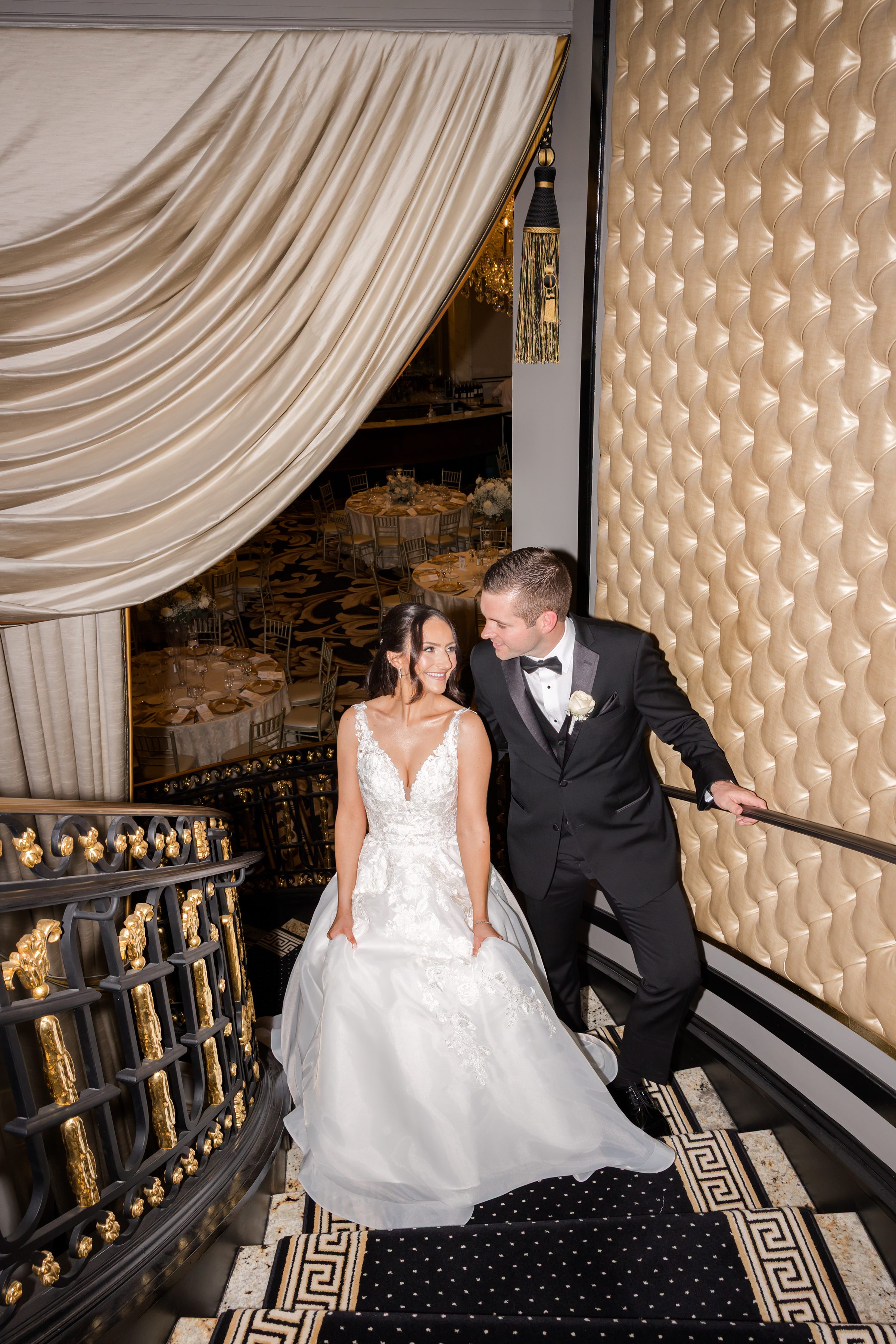 Bride and groom smiling at each other by the stairs 