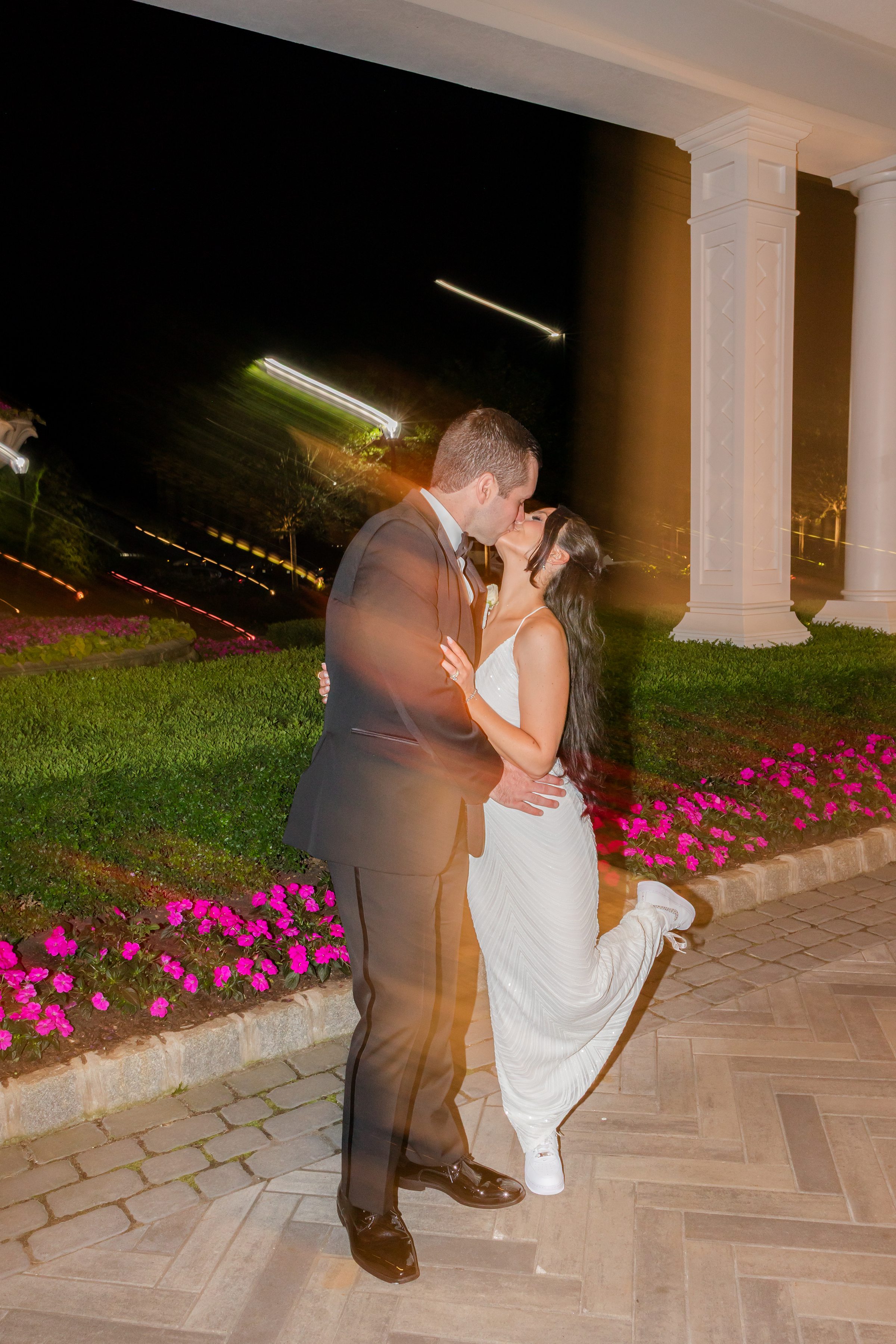 The couple is kissing together, the bride is wearing white bodycon dress 