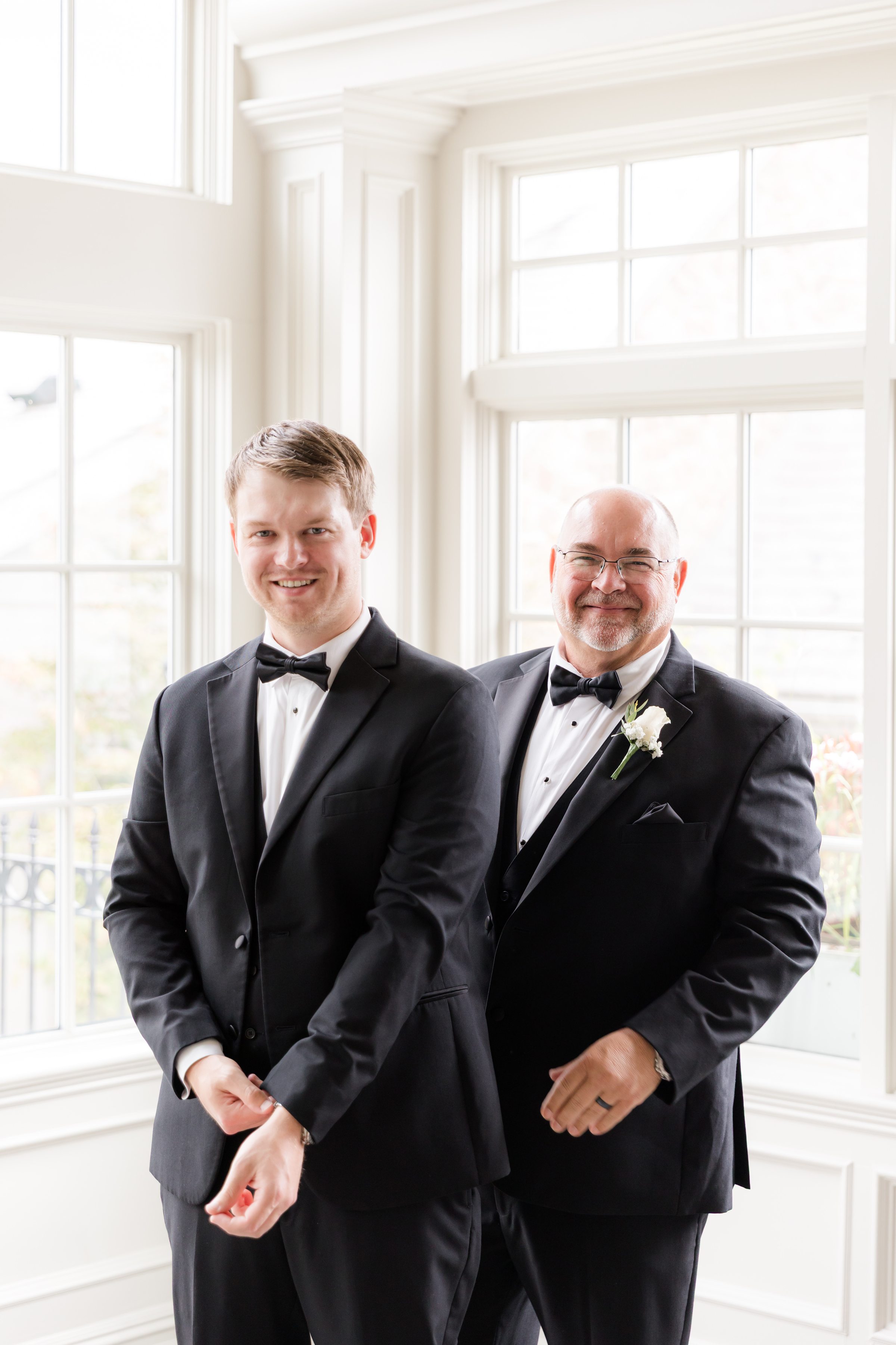 Portrait of the groom and his dad, standing side-by-side, by the window
