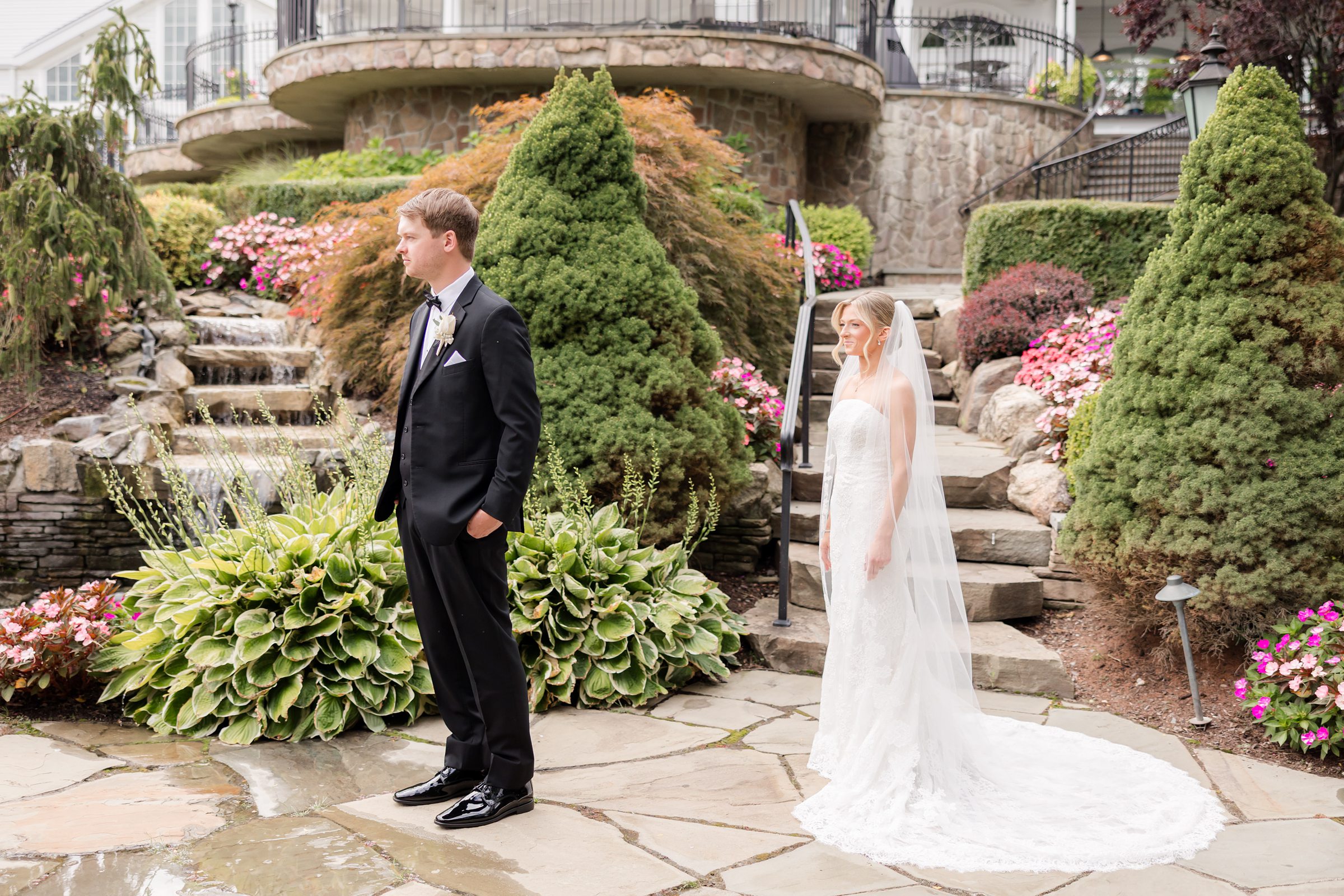 Bride standing behind the groom in the garden for the first look
