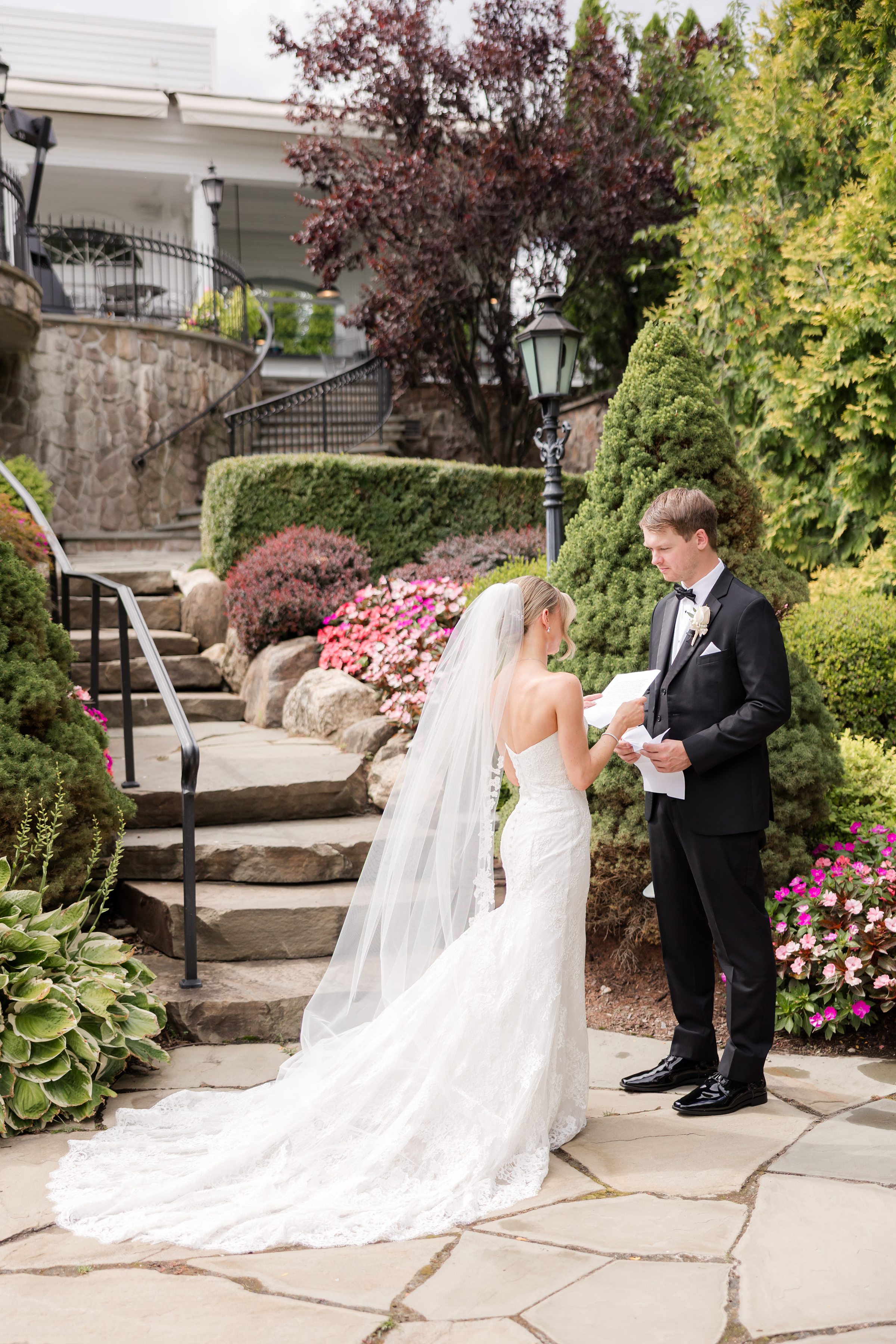 Bride and groom facing each other in the garden while the bride is reading her vows
