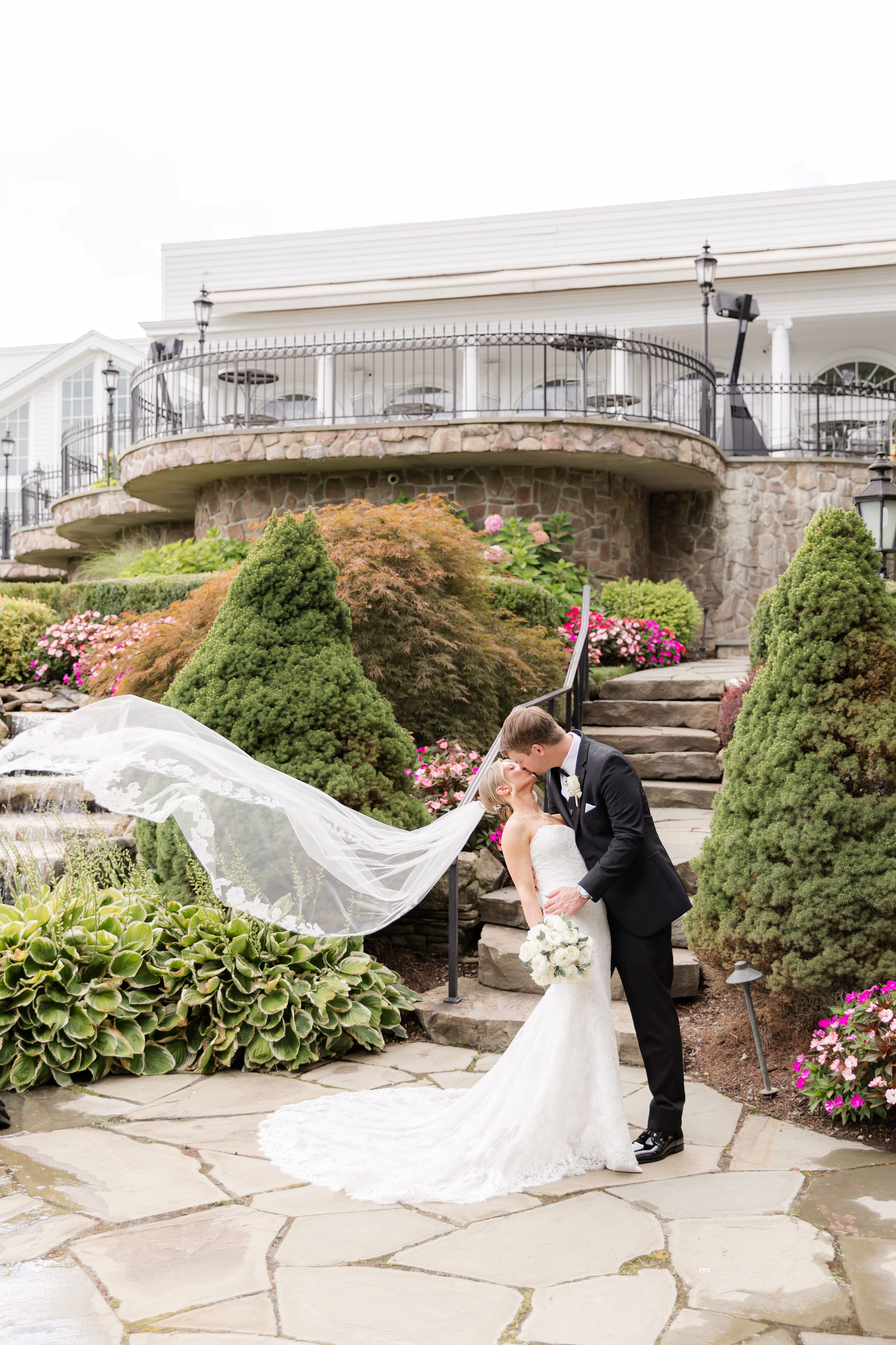 Bride and groom kissing at Park Savoy's garden while the bride's veil is blown by the wind