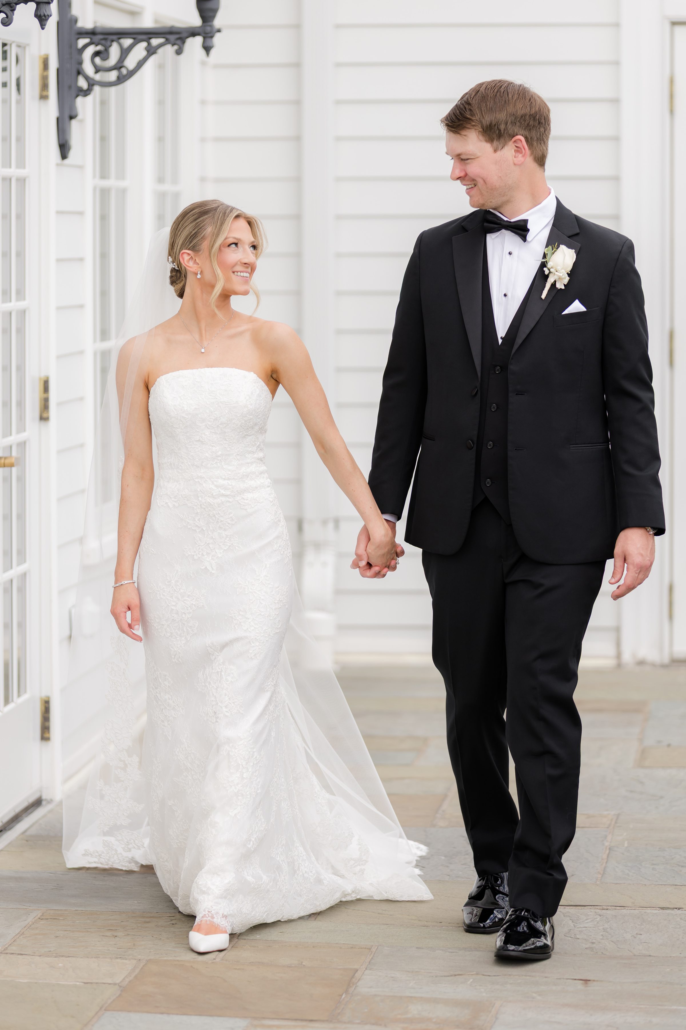 Bride and groom walking together hand-in-hand while looking at each other