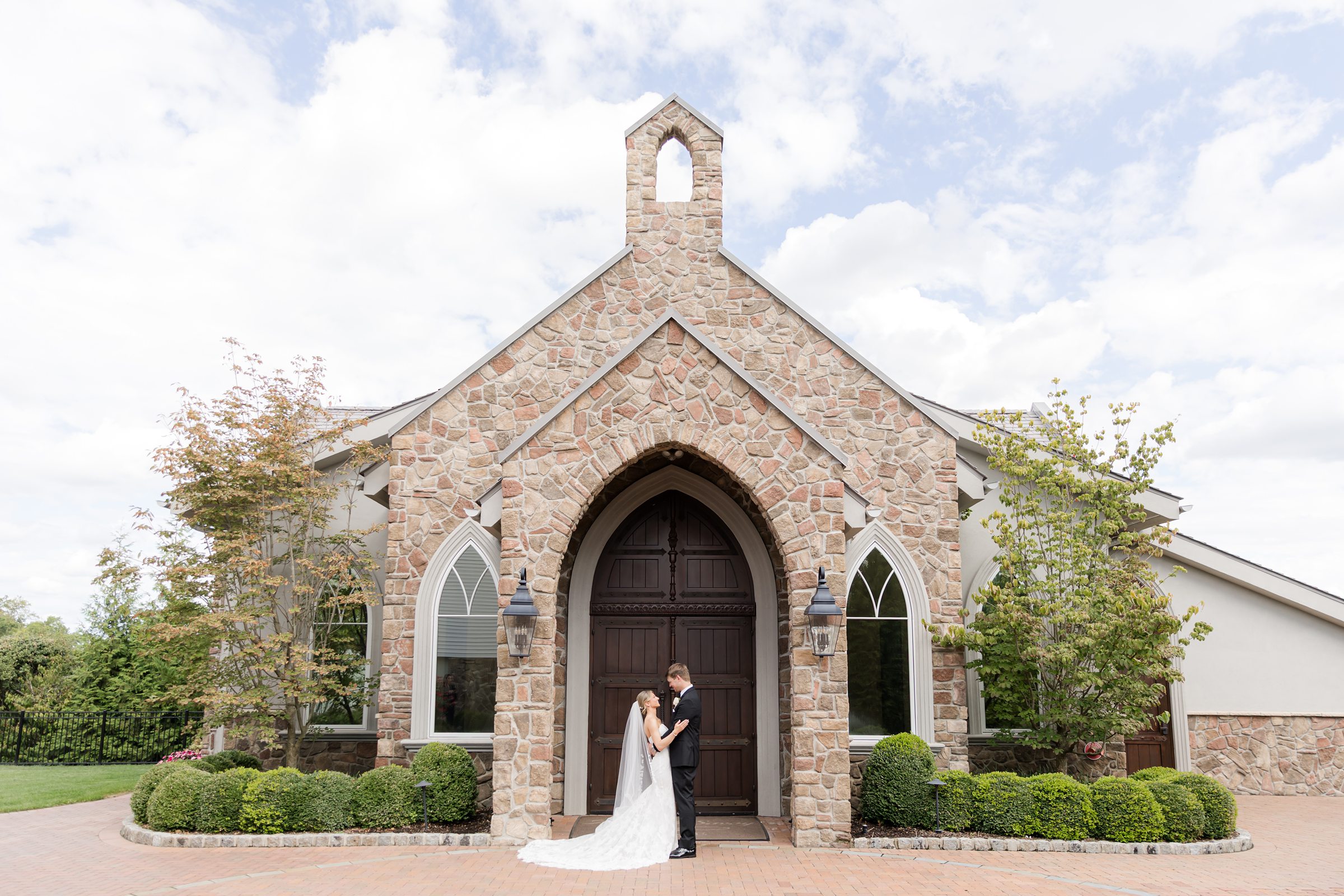 Landscape photo of bride and groom facing each other outside the chapel