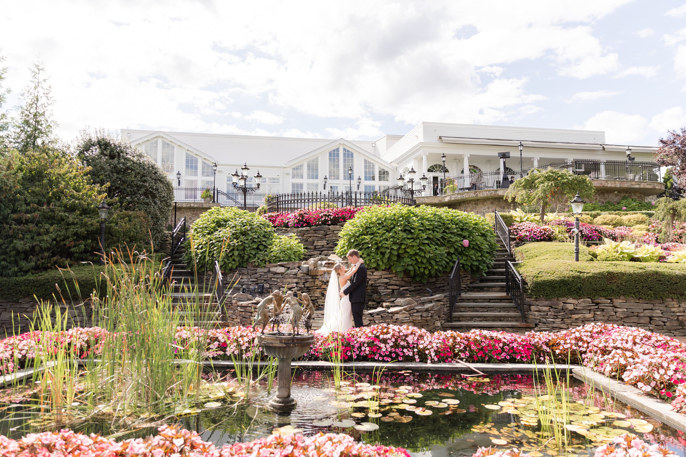 Bride and groom in the garden by the fountain with their arms wrapped around each other