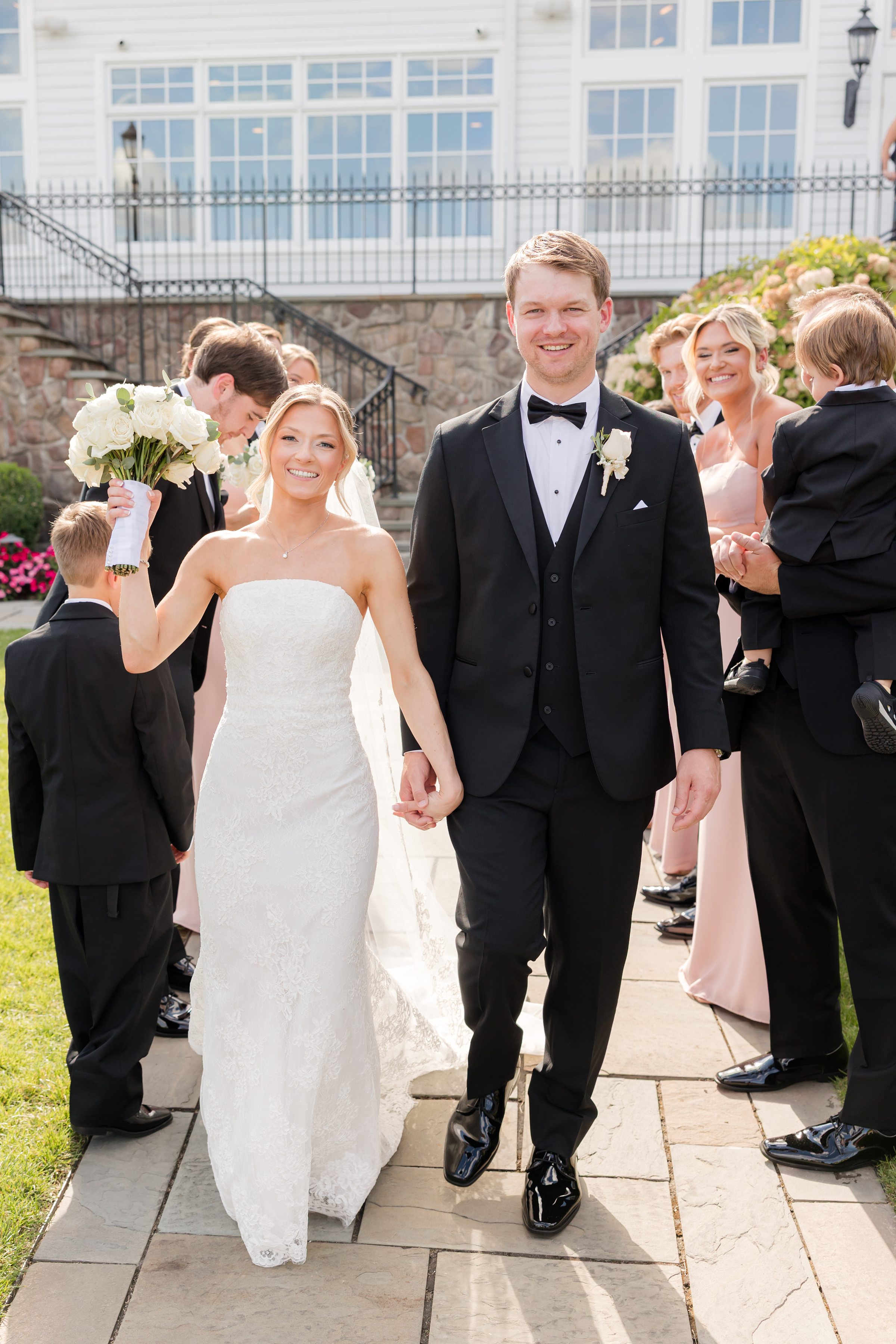 Bride and groom holding hands as the wedding party is behind them