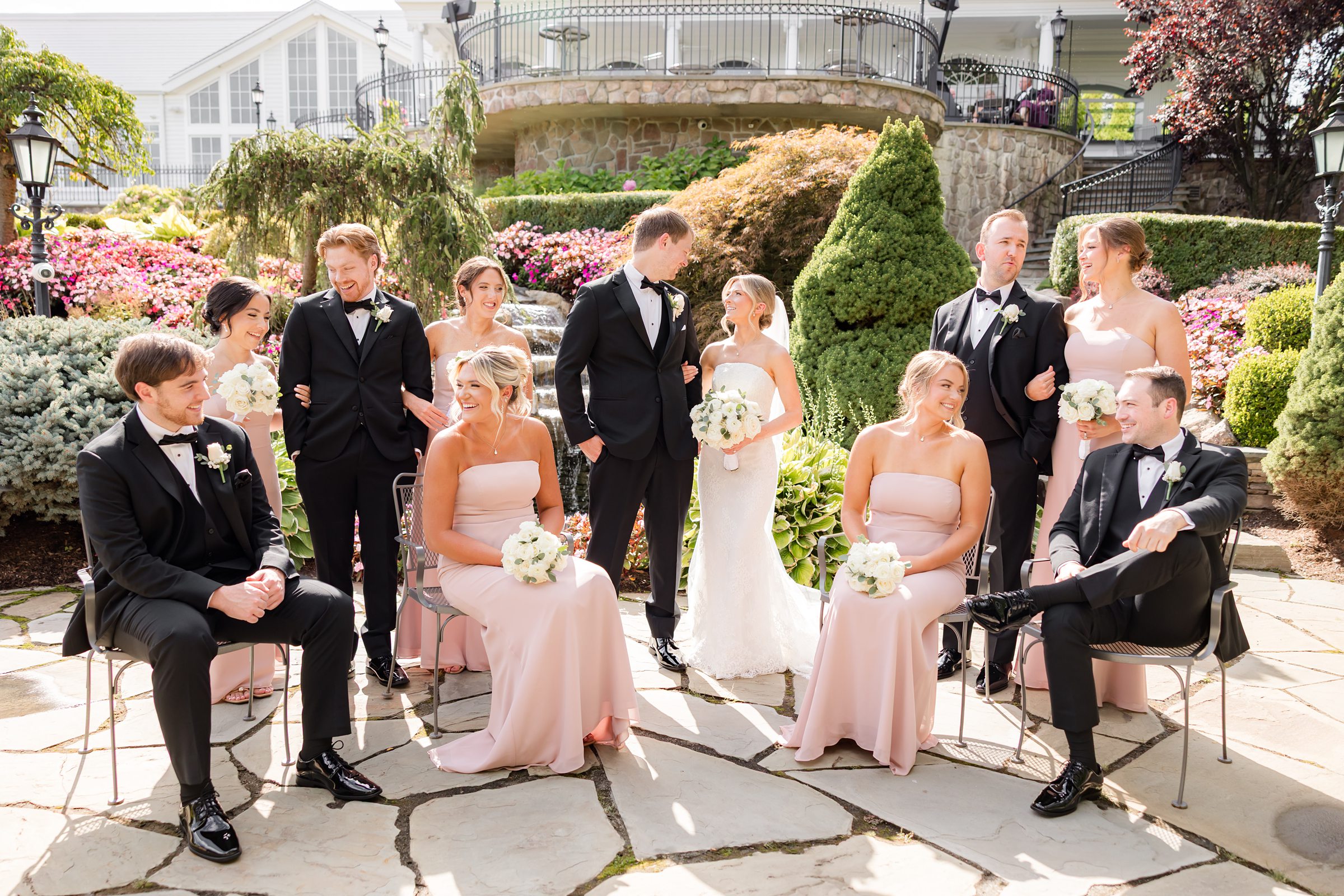 Landscape photo of bride and groom together with wedding party at the garden, looking at one another