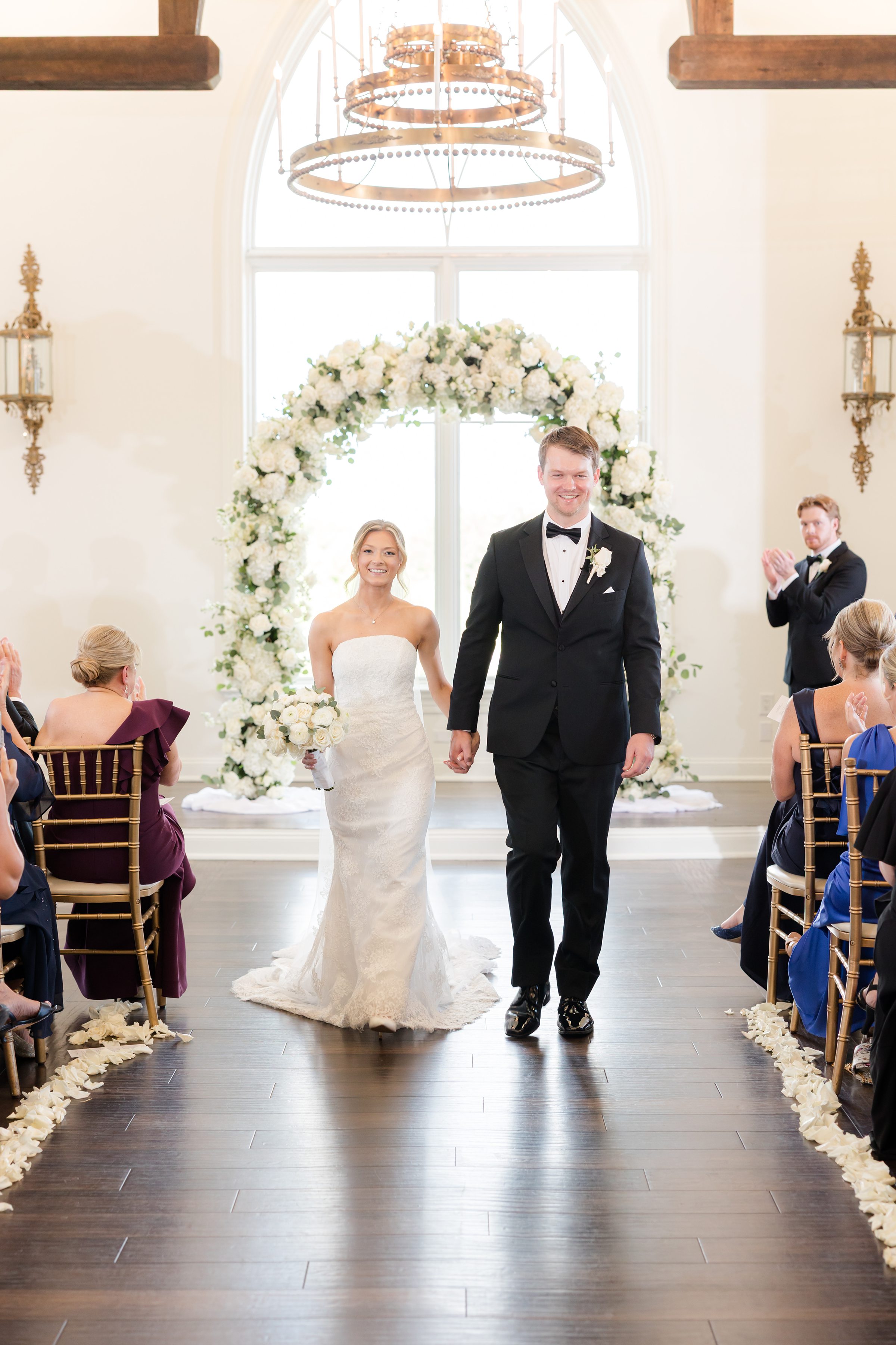 Bride and groom walking down a wooden aisle, hand-in-hand while exiting the chapel
