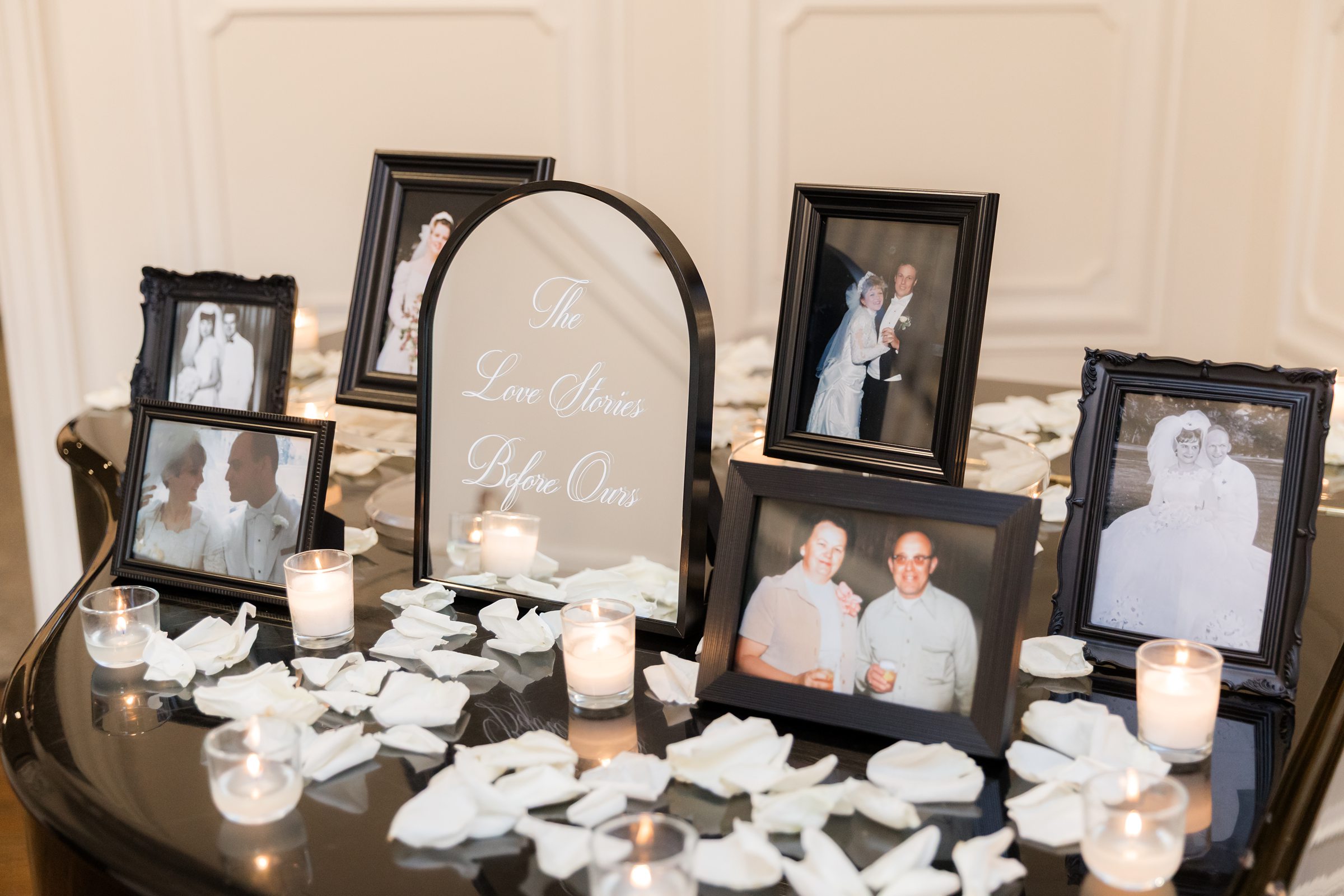 Photo of the couple's parents and grandparents on top of the piano, filled with white rose petals and candles