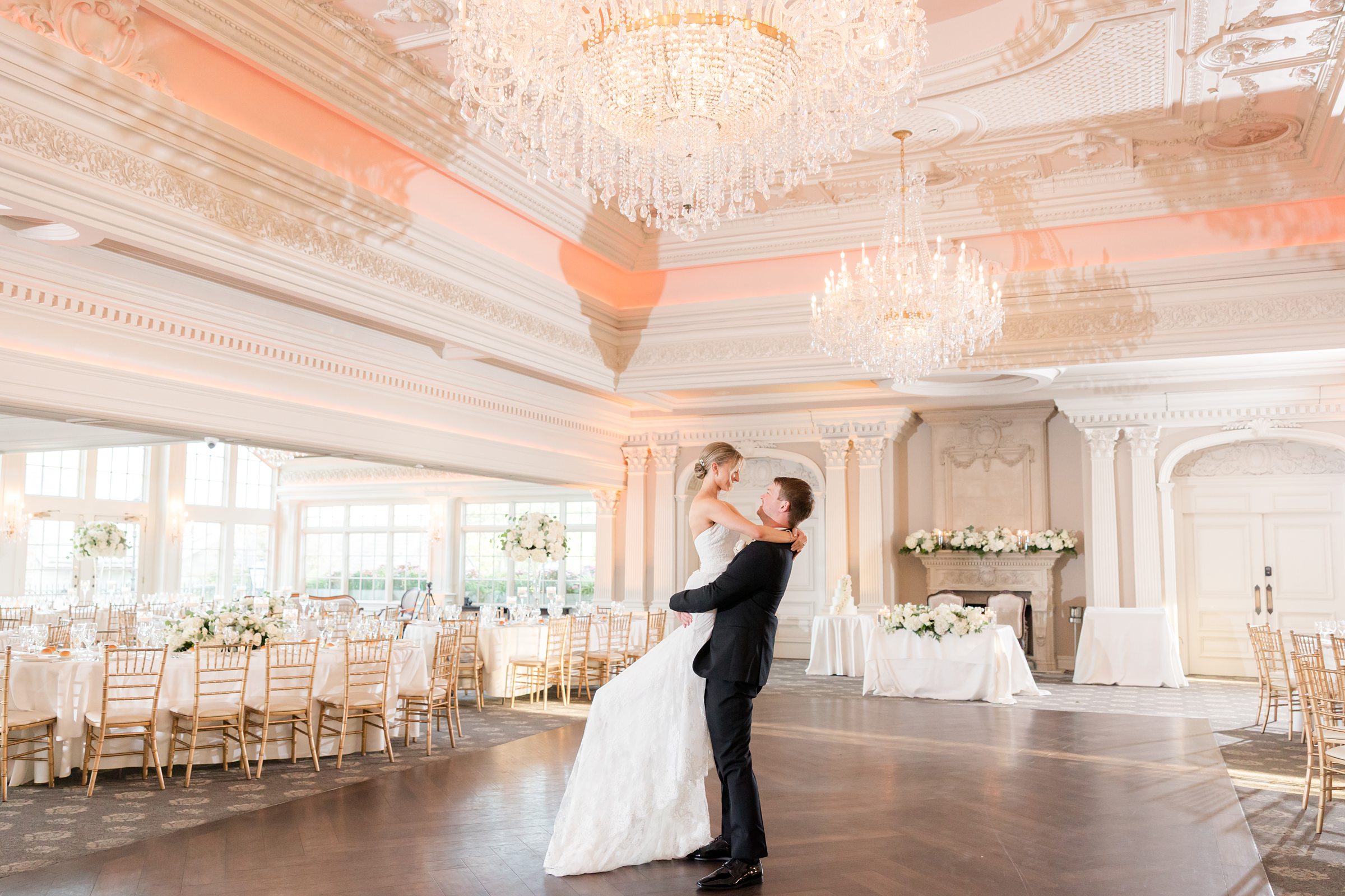 Groom carrying the bride in an empty ballroom while looking into each other's eyes