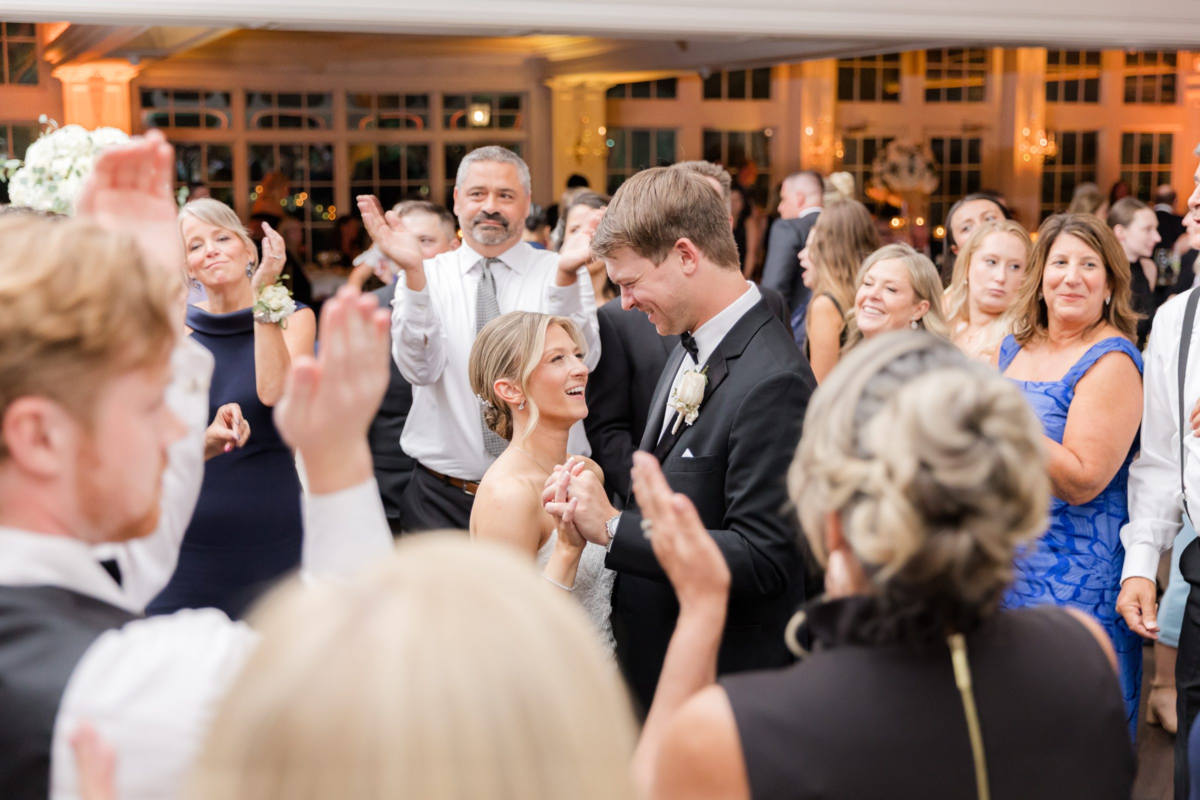 Bride and groom holding each other and smiling while dancing with guests