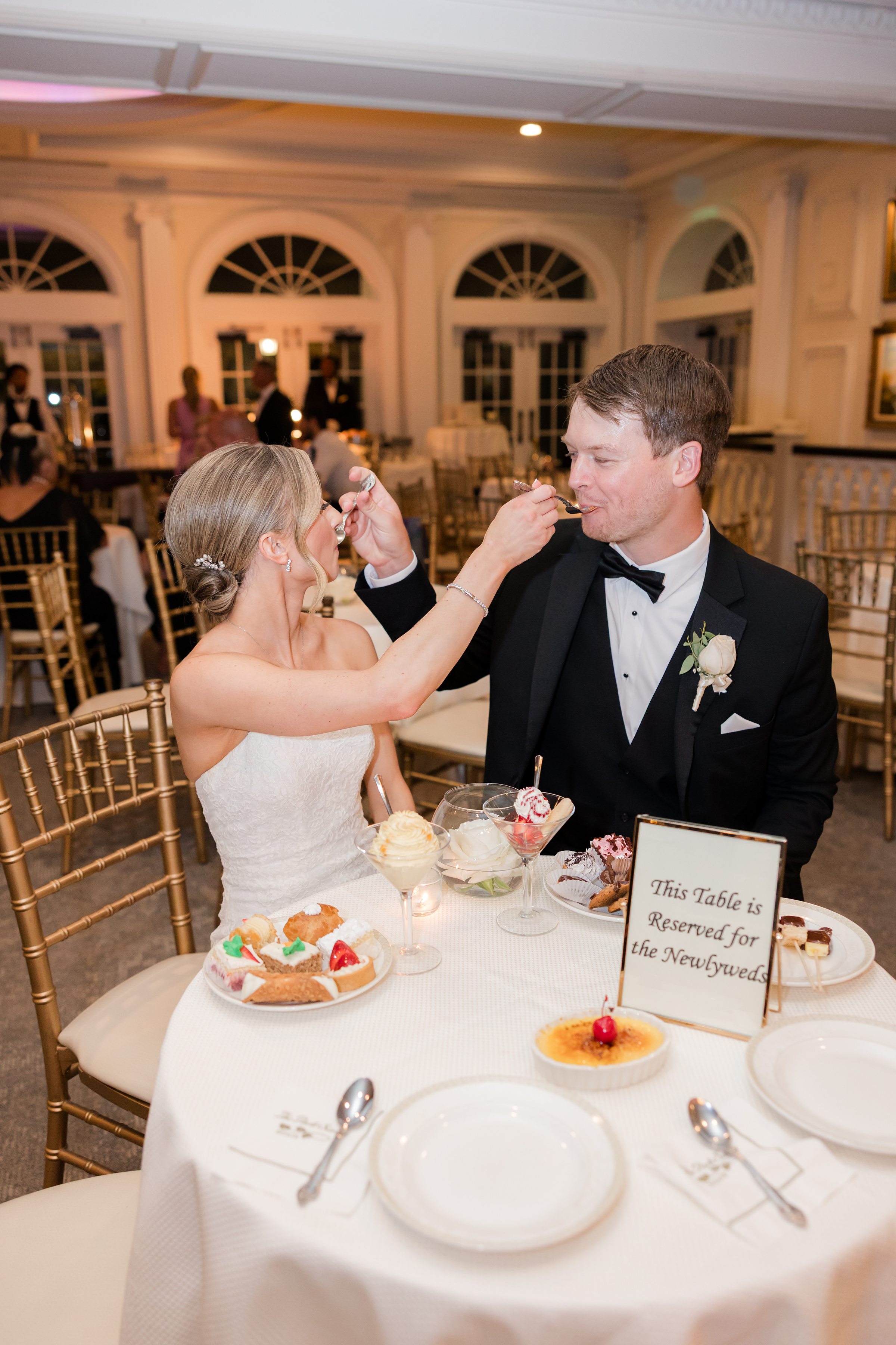 Photo of bride and groom feeding each other desserts 
