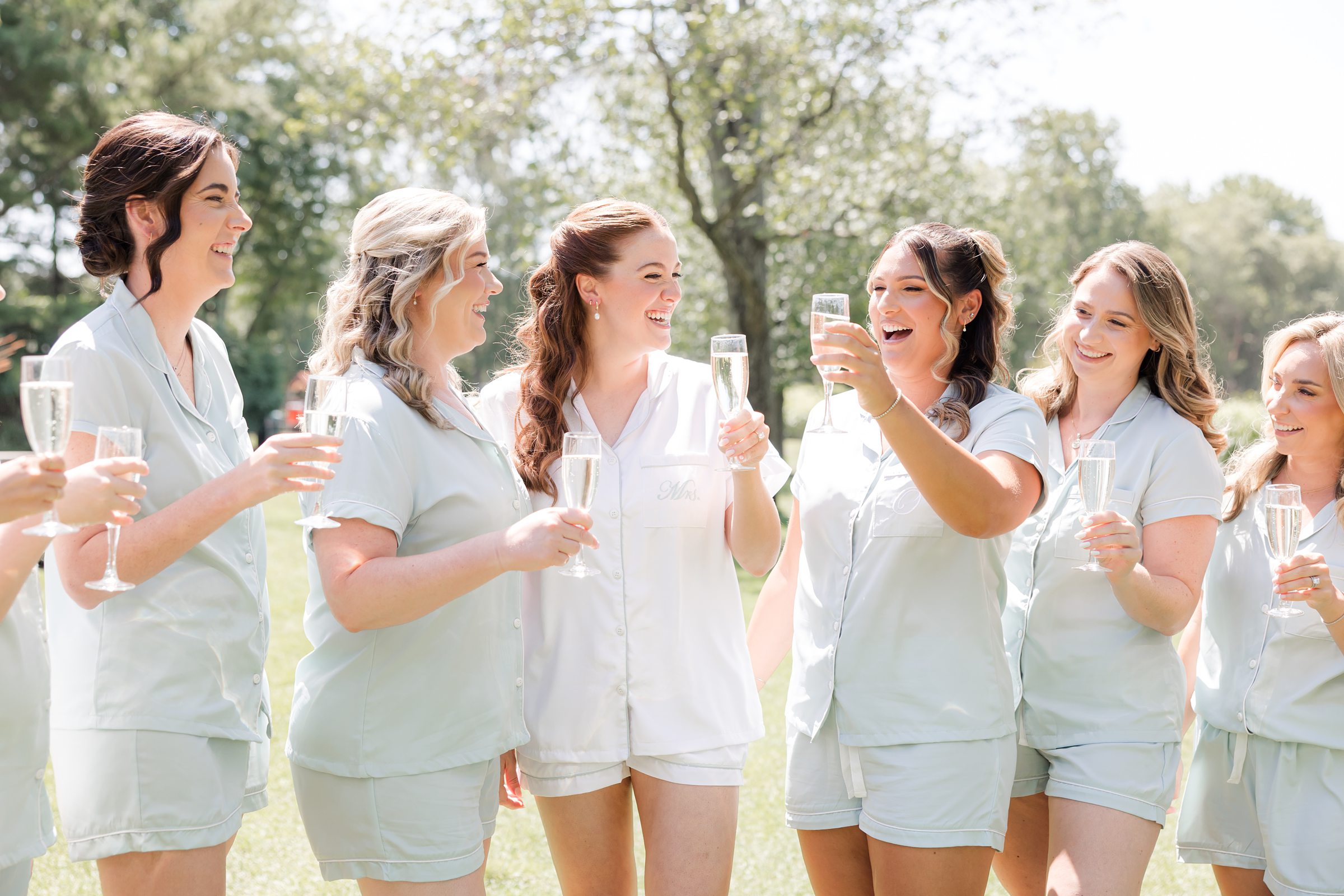 a close-up shot of bride laughing with bridesmaids while holding a glass of champagne