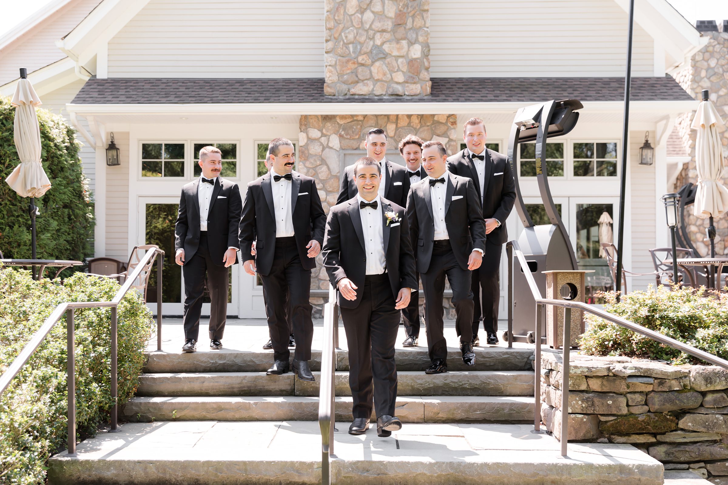 a landscape picture of groom with groomsmen walking down the stairs fully dressed up 