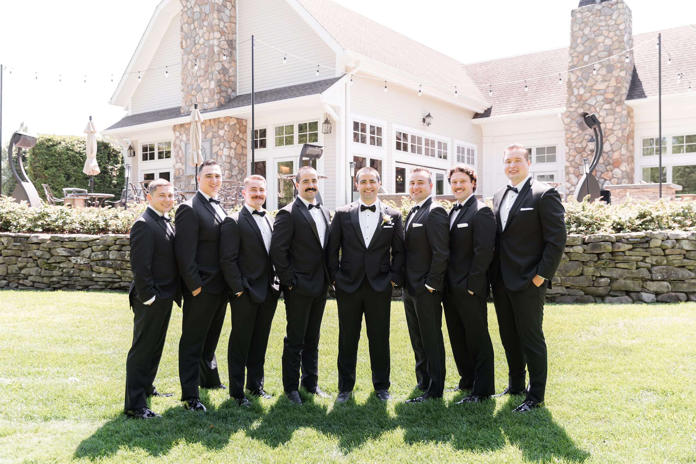a landscape picture of groom with groomsmen standing together wearing black tuxedo