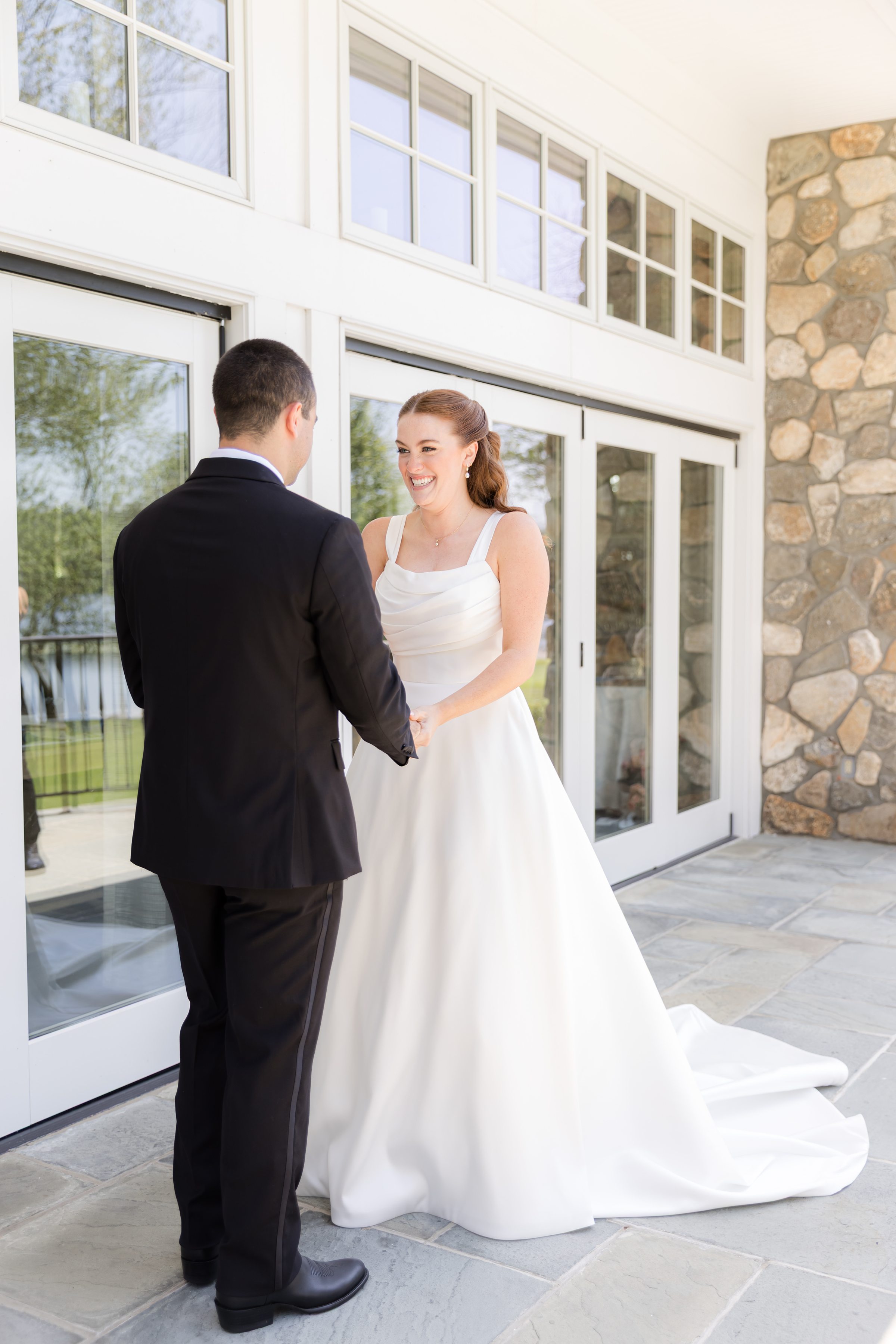 picture of bride and groom holding each other's hands while smiling together 