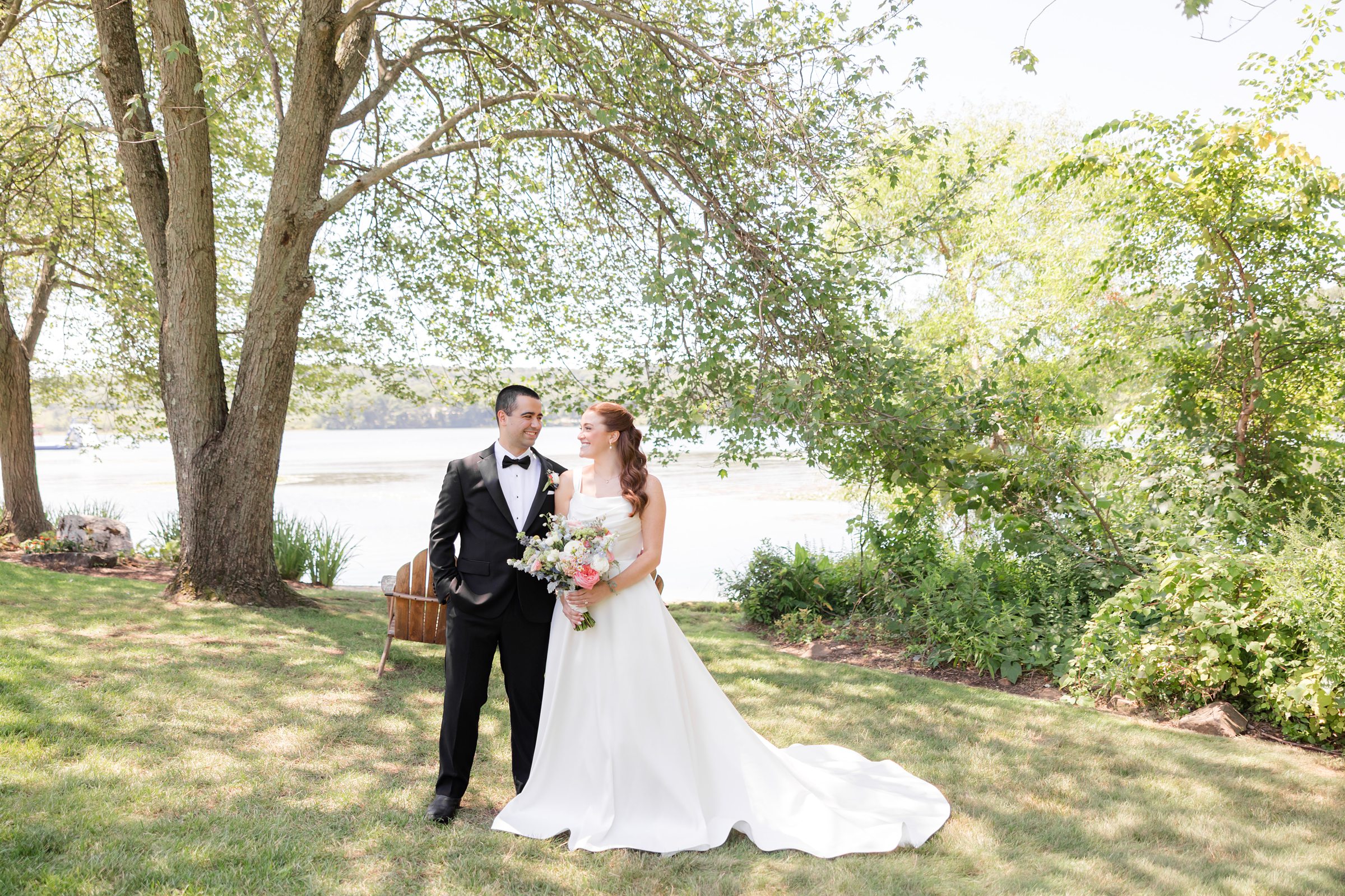 landscape picture of bride and groom by the tree, looking at each other 