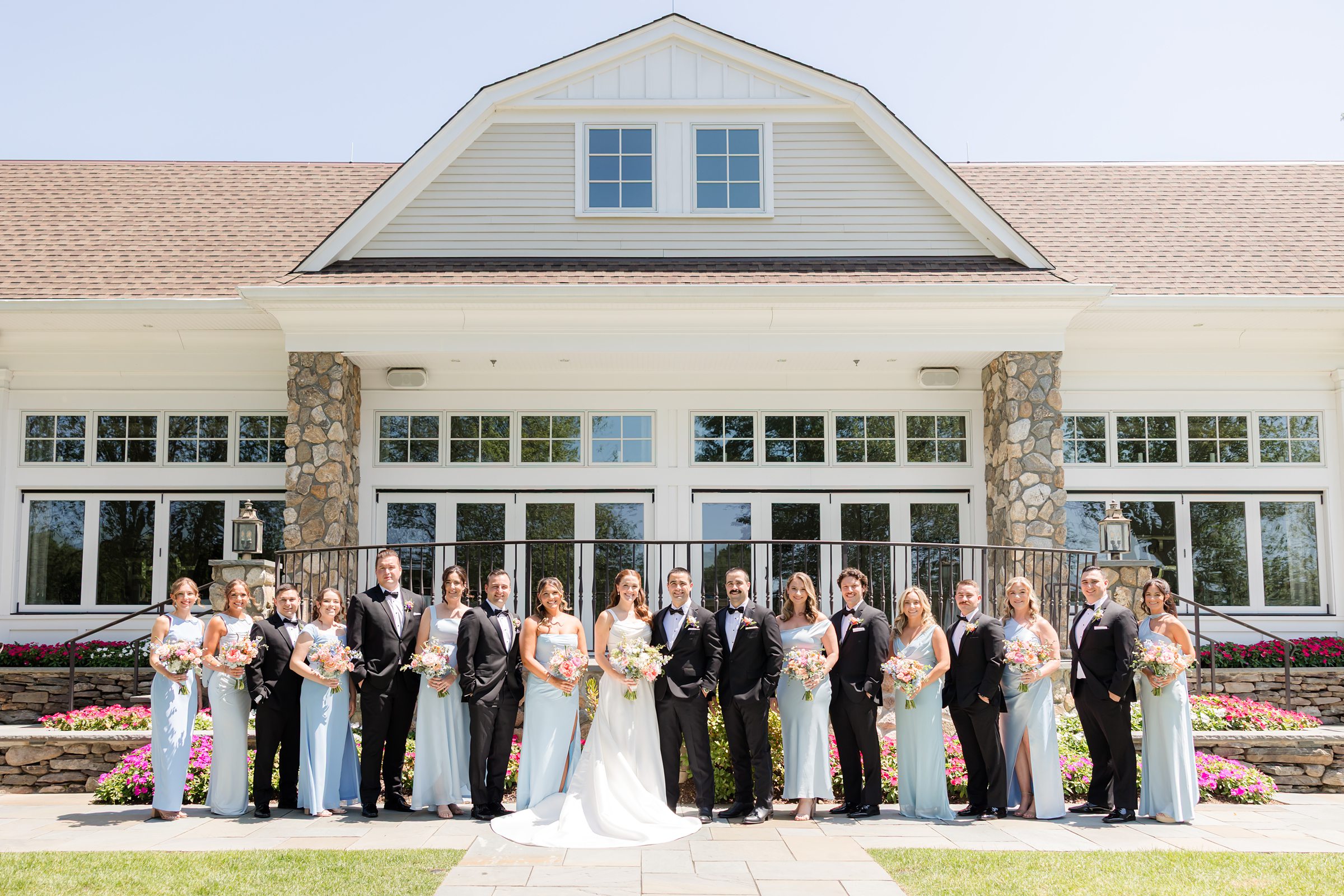 a landscape picture of bride, groom, groomsmen and bridesmaid holding flowers at Indian Trail Club 