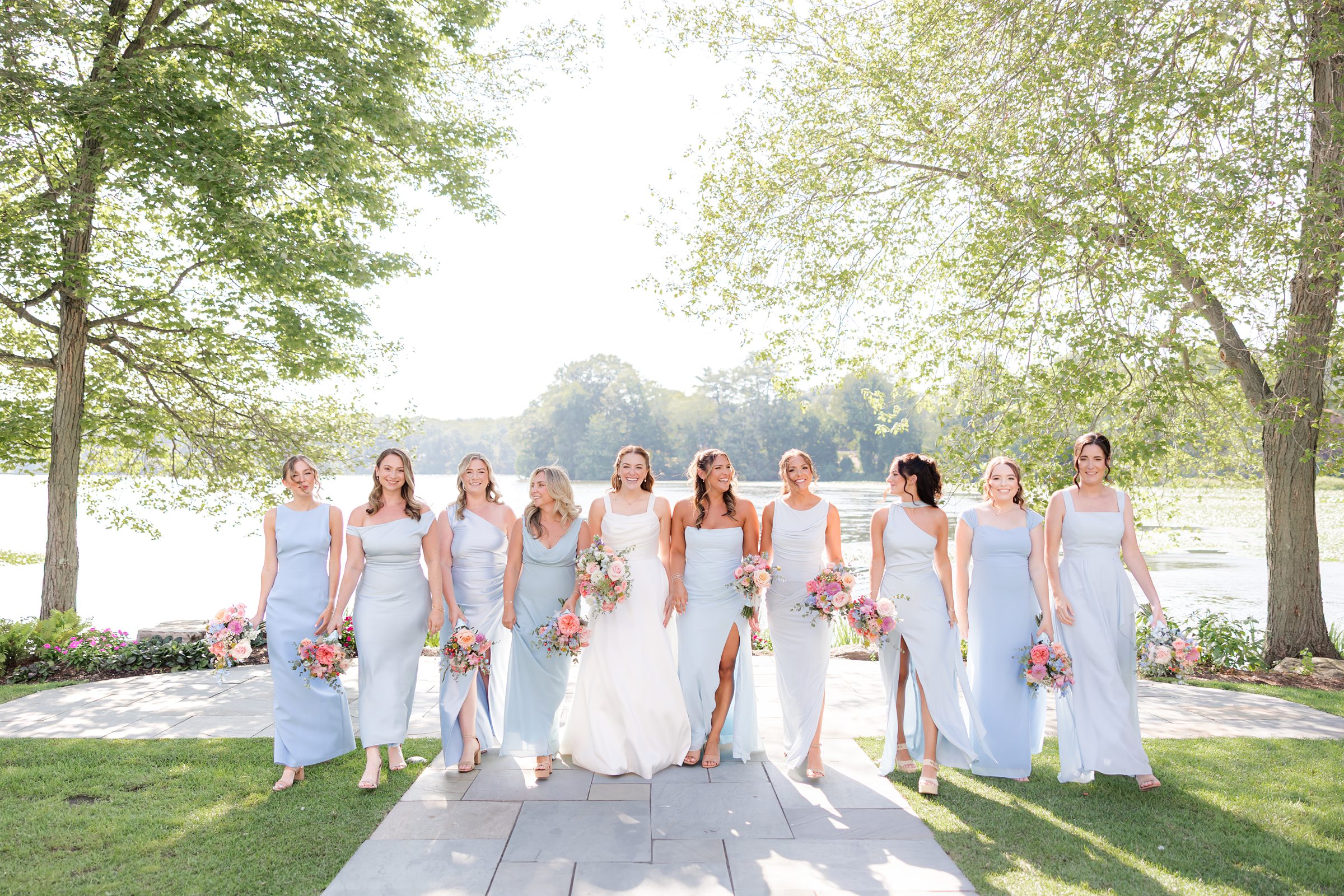 landscape photo of bride with bridesmaids by the lake, bridesmaids are wearing powder blue dresses