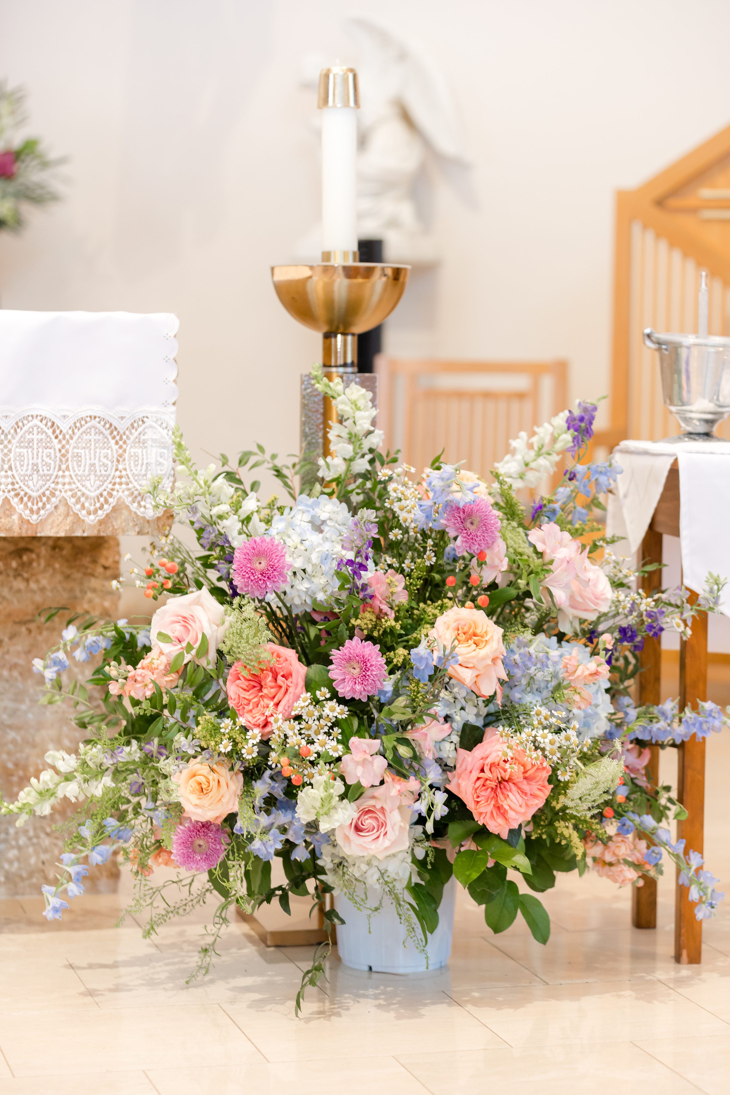 a close up picture of the flower bouquet placed by the altar, orange, violet, pink, blue flowers 